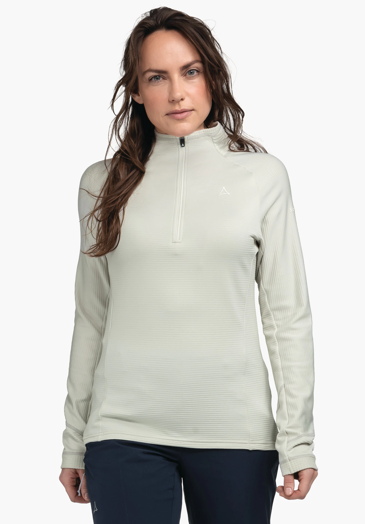 Longsleeve Style Cascata WMS lichtgrijze longsleeve met Schöffel-logo, halve ritssluiting; vrouw staat frontaal, armen ontspannen, draagt een donkerblauwe broek, witte achtergrond.