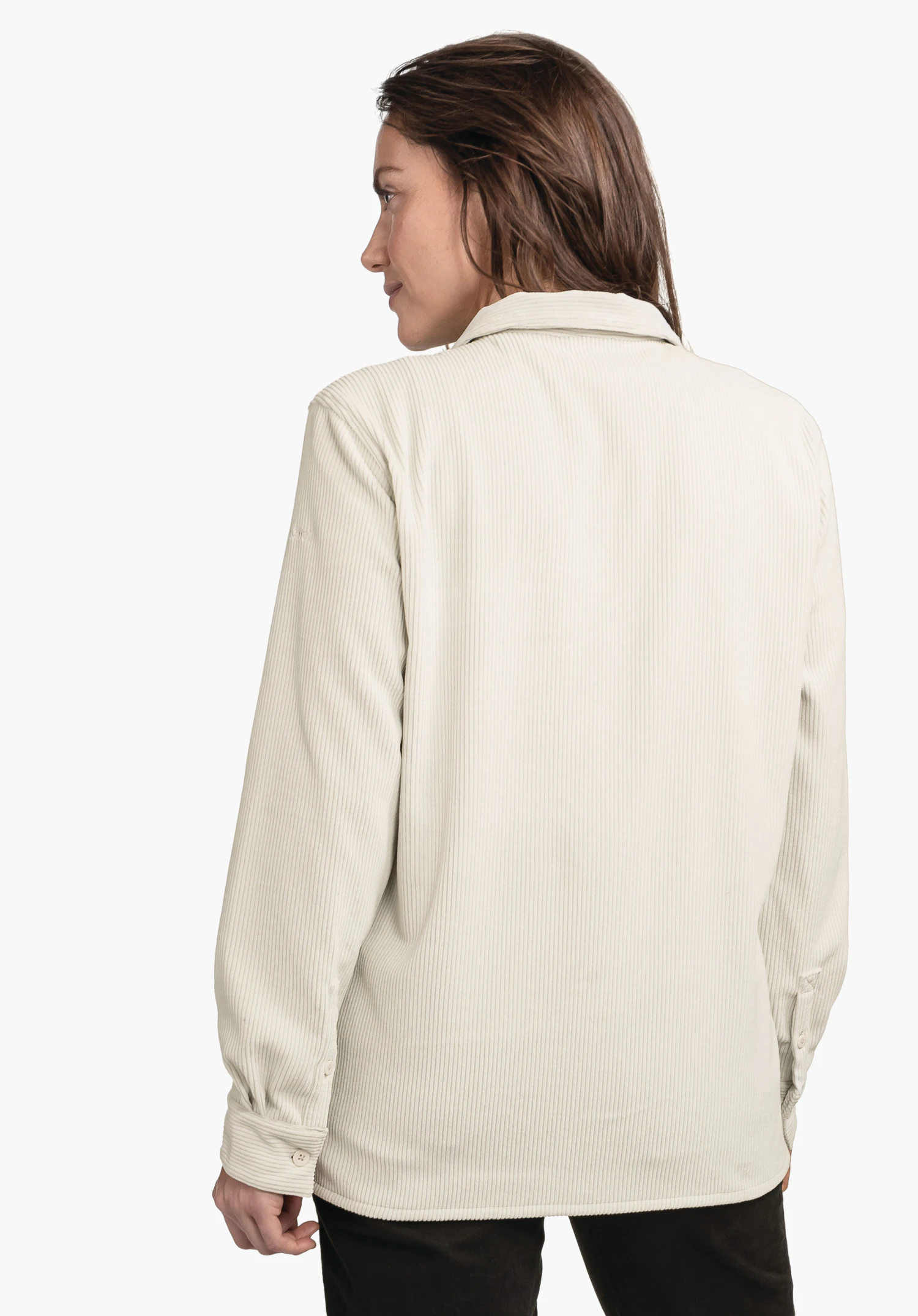 Blouse Style Lodos WMS lichtwitte overhemdjas, achteraanzicht; gedragen door een staande persoon met het hoofd naar links gedraaid, bruin haar, zwarte broek, lichte effen achtergrond.