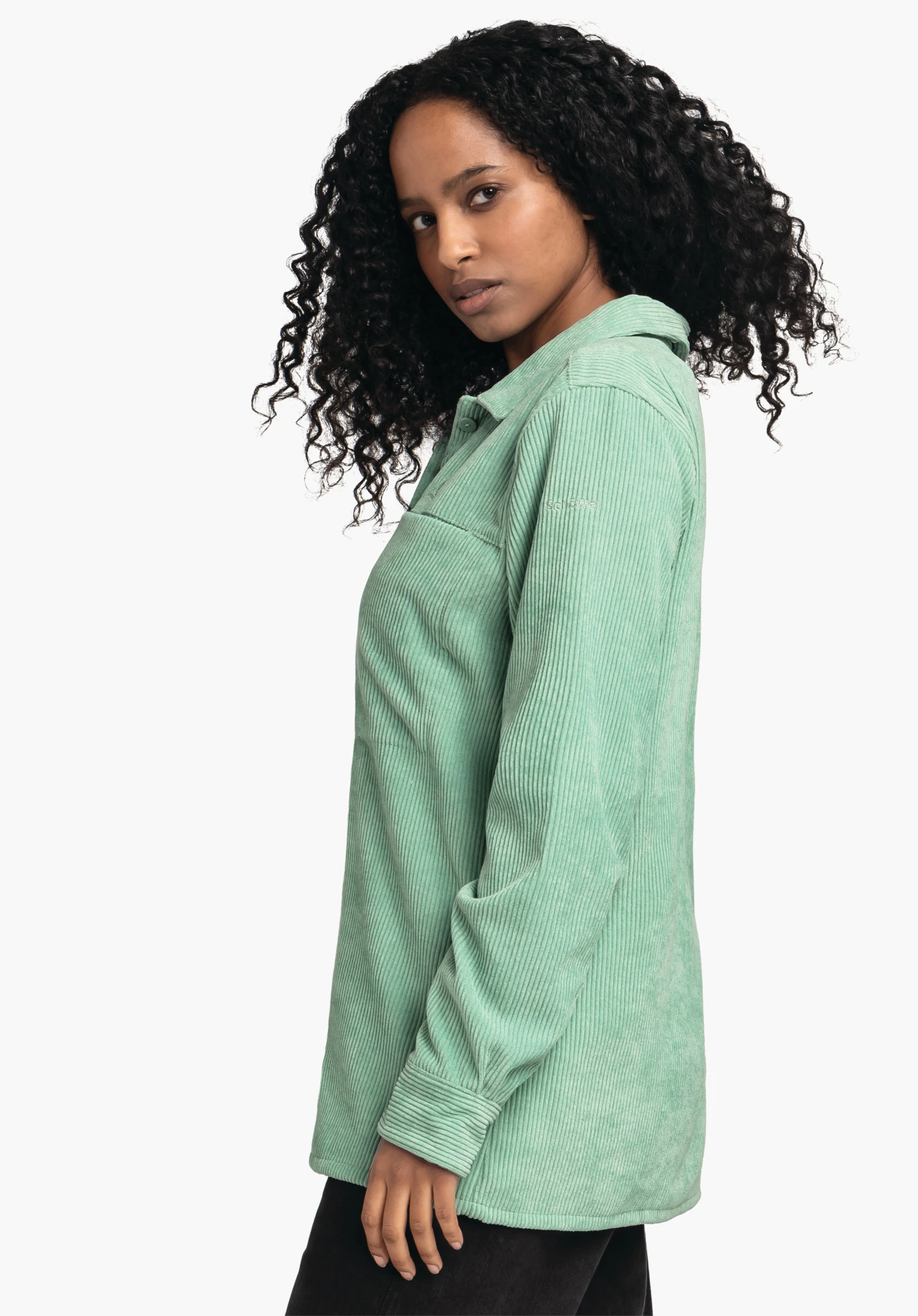 Blouse Style Lodos WMS lichtgroen geribd longsleeve shirt gedragen door een persoon; de persoon kijkt zijwaarts en heeft zwart krullend haar; neutrale witte achtergrond.
