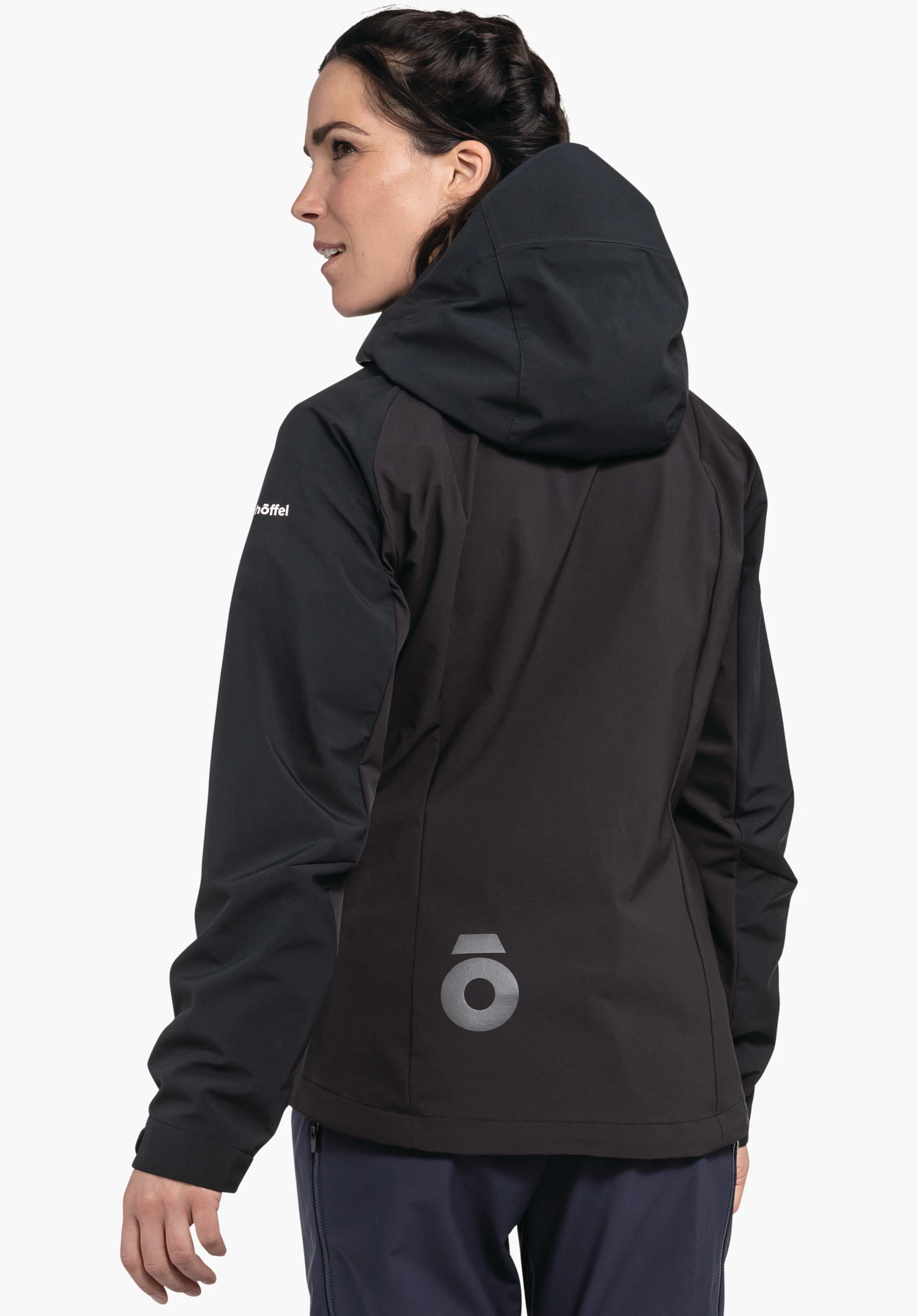 Hybrid Jk Style Salza WMS Frau trägt dunkelgraue Jacke mit schwarzer Kapuze, steht leicht nach links gedreht vor weißem Hintergrund. Auf Ärmelschrift: "Schöffel".