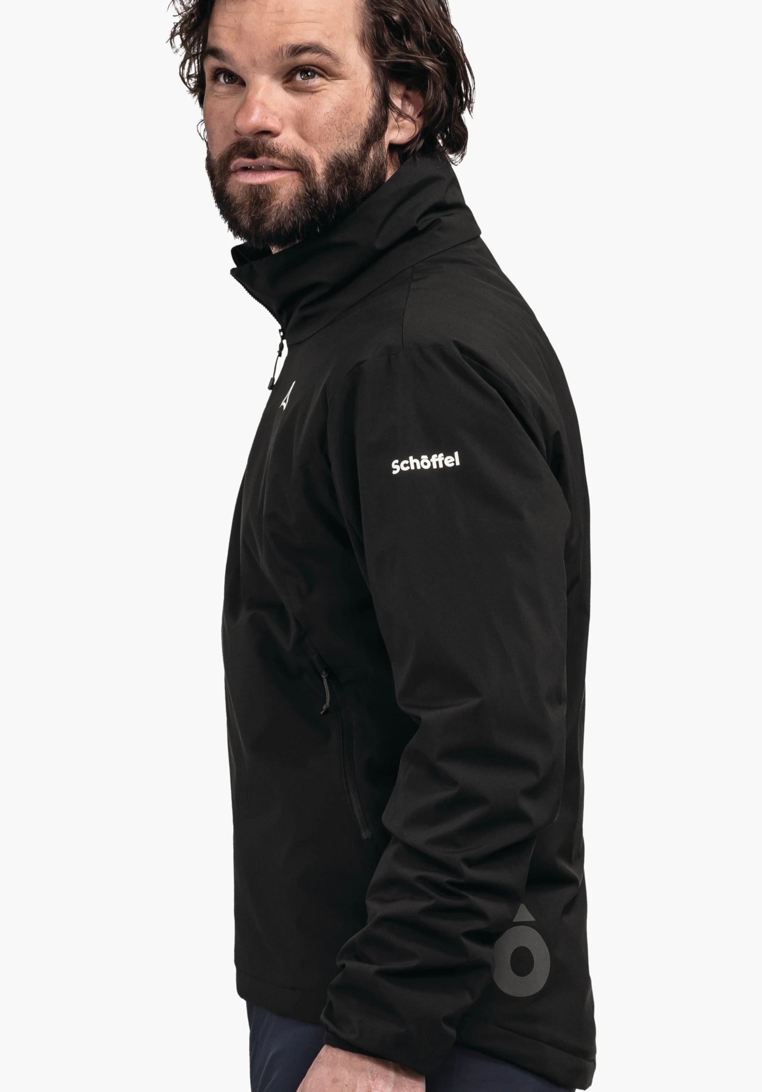 Ins Jacket Style Salza MNS veste noire portée de profil par un homme regardant vers le haut; texte "Schöffel" sur la manche, logo Schöffel sur la poitrine et l’ourlet; fond clair uni, pantalon bleu foncé.