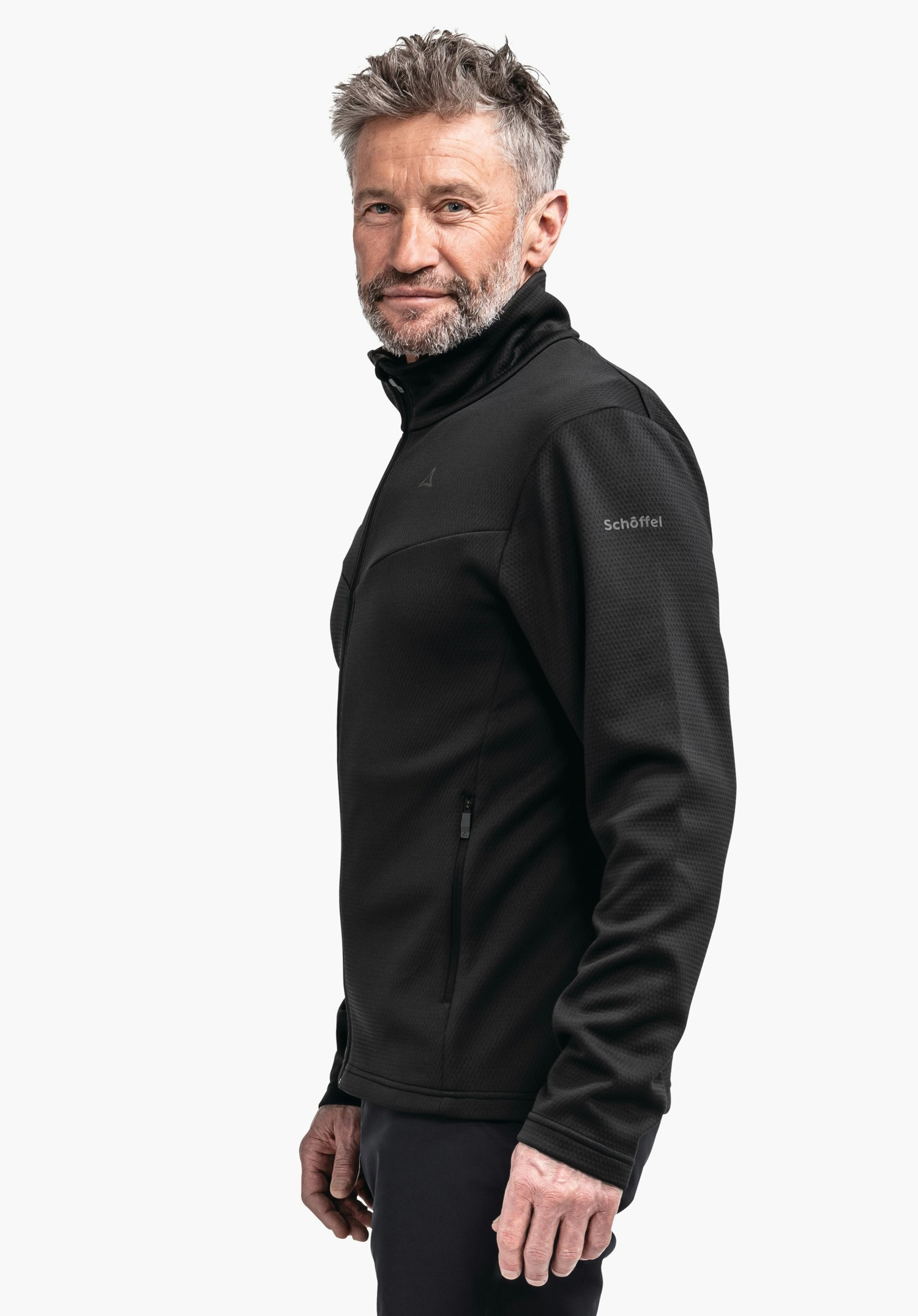 Fleece Jk Style Pine MNS Schwarze Fleecejacke, getragen von stehendem Mann; seitliche Ansicht, Schöffel-Logo auf der Brust, Schriftzug "Schöffel" auf dem Ärmel; neutraler weißer Hintergrund.