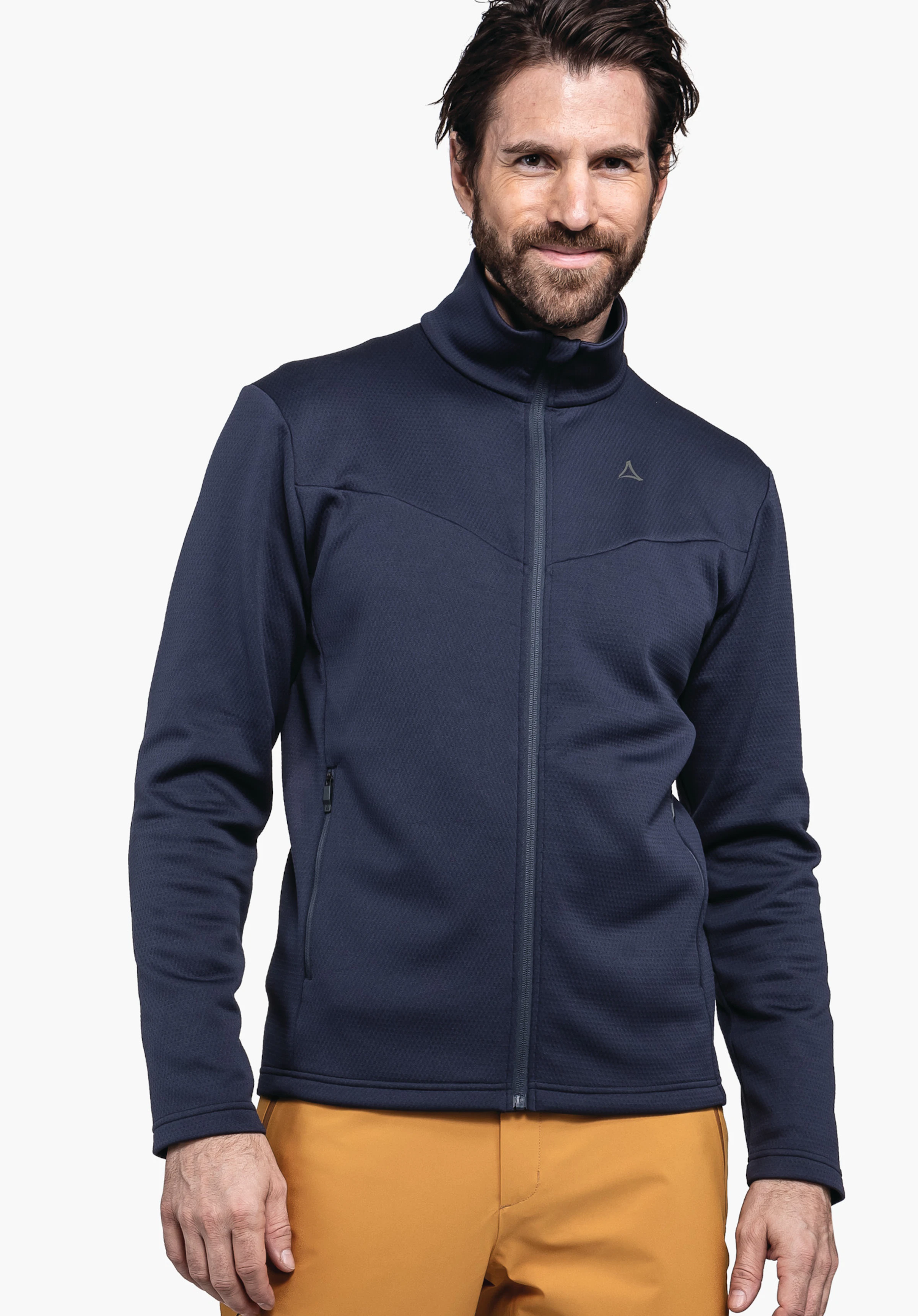 Fleece Jk Style Pine MNS donkerblauwe jas, gedragen door een glimlachende man; Schöffel-logo op de borst; oranje broek; staand voor een witte achtergrond.