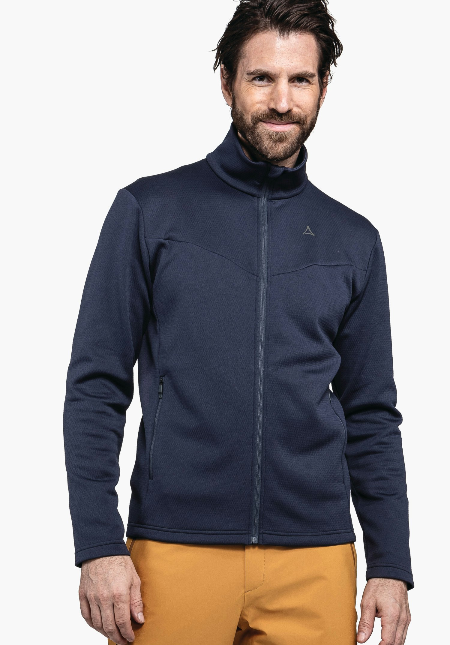 Fleece Jk Style Pine MNS Dunkelblaue Jacke, von einem lächelnden Mann getragen; Schöffel-Logo auf der Brust; orange Hose; stehend vor weißem Hintergrund.