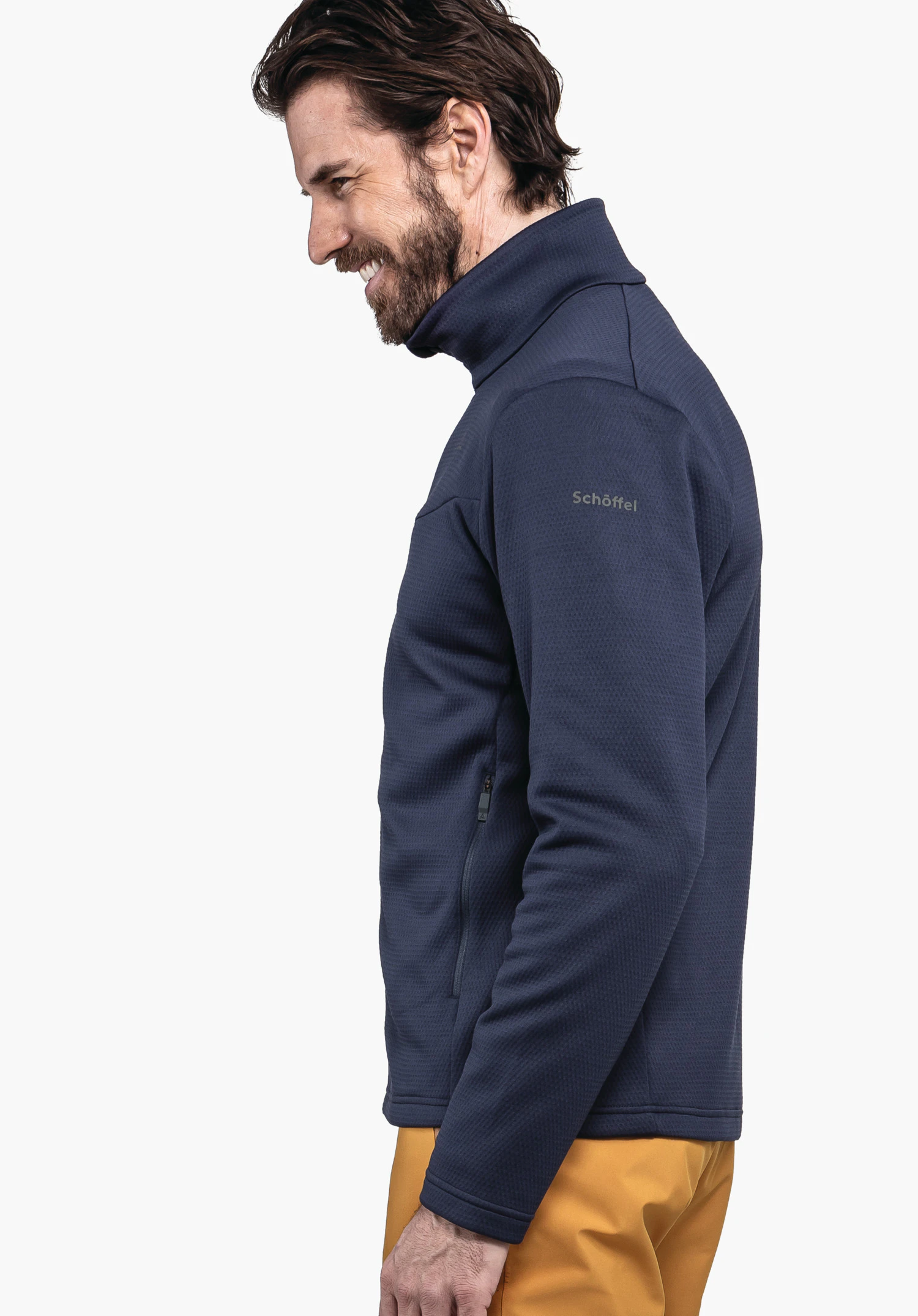 Fleece Jk Style Pine MNS dark blue fleece jacket worn side-on by a smiling man with relaxed arms; standing in front of a white background with yellow trousers. Text on sleeve: Schöffel.
