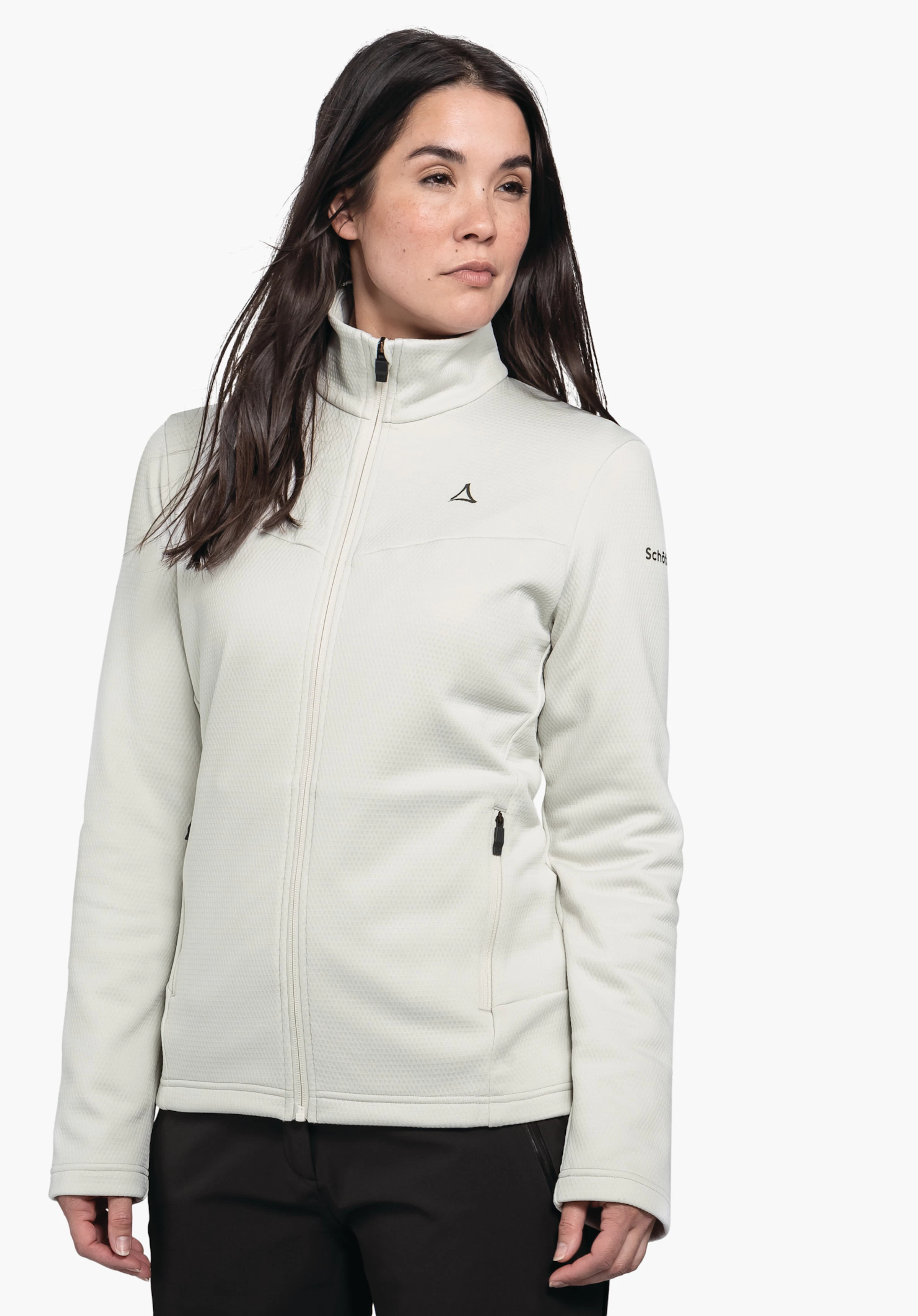 Fleece Jk Style Pine WMS witte damesjas met Schöffel-logo op de borst; gedragen door een vrouw met donkerbruin haar, licht zijwaarts staand voor een witte achtergrond, zwarte broek. Tekst: "Schöffel".