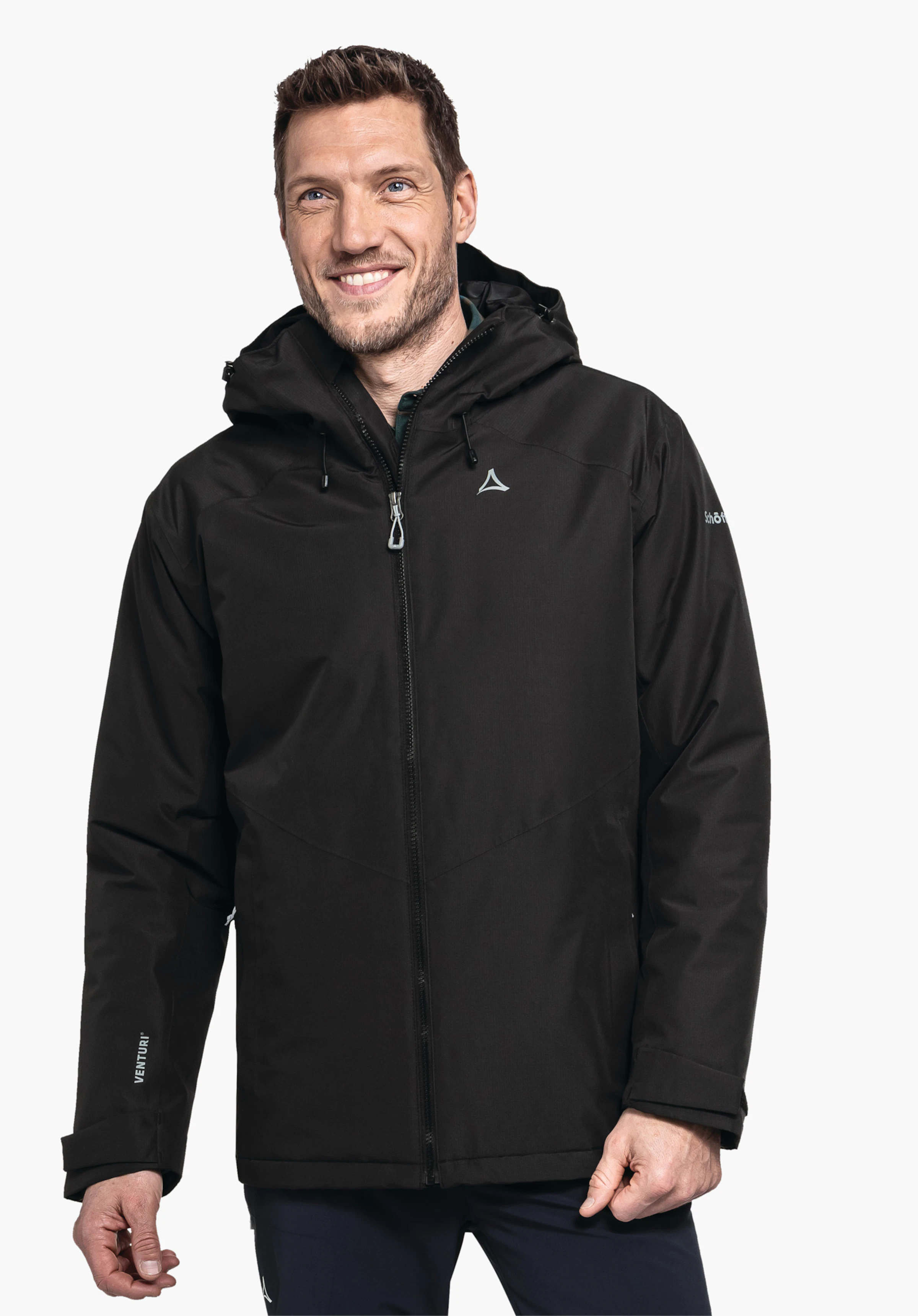 Ins Jacket Style Wildkar MNS zwarte jas met capuchon, gedragen door een glimlachende man tegen een lichte achtergrond; Schöffel-logo op de borst. Tekst op de mouw: “VENTURI”; Schöffel.