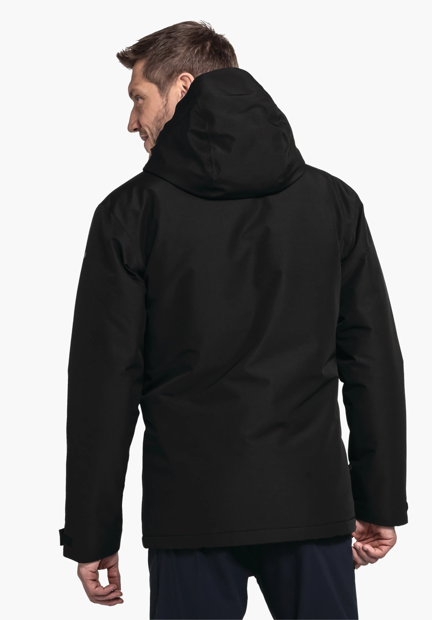 Ins Jacket Style Wildkar MNS Schwarze Kapuzenjacke an einem Mann, Rückenansicht; Kopf leicht nach links gedreht; dunkelblaue Hose; neutraler weißer Studiohintergrund.