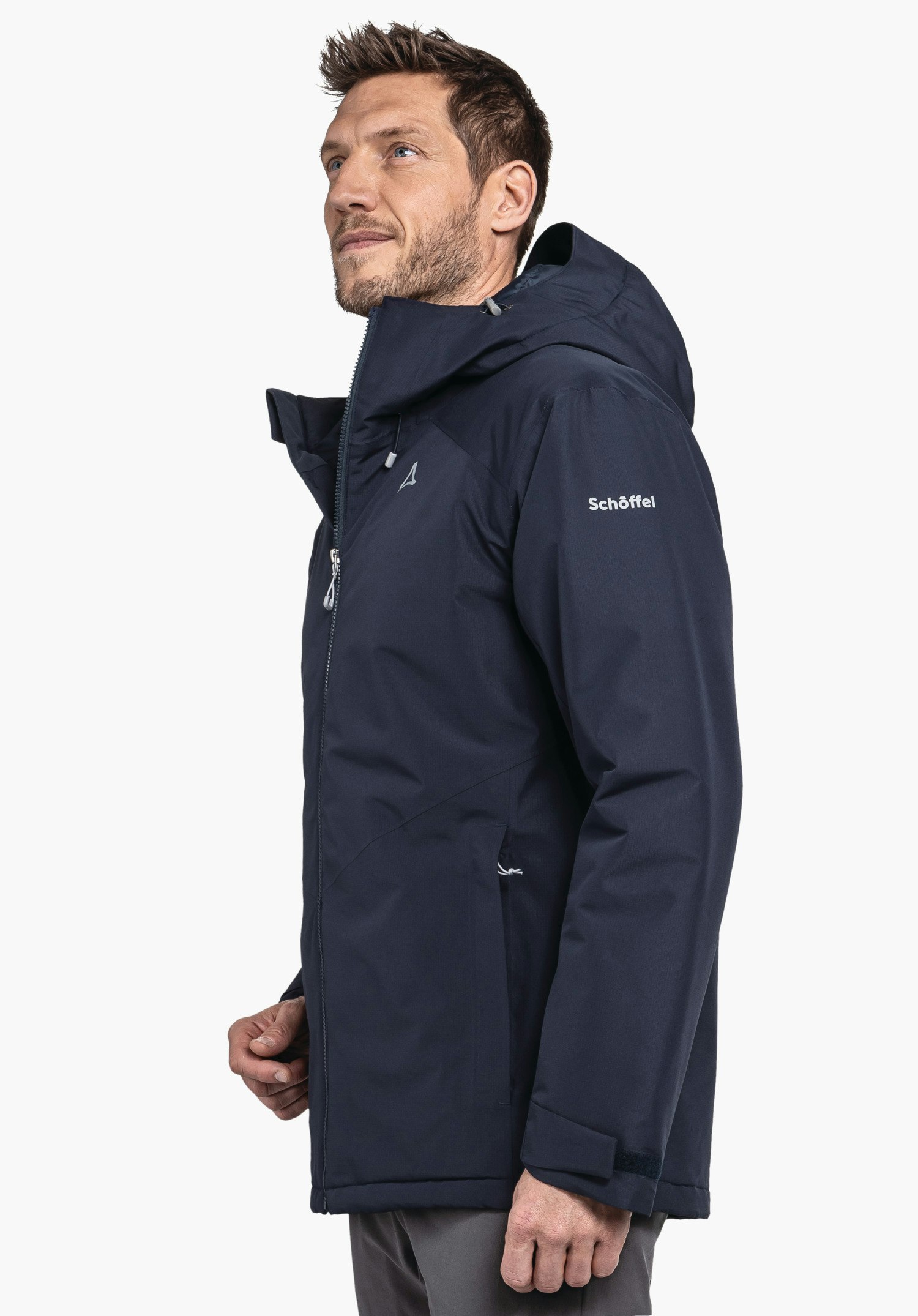 Ins Jacket Style Wildkar MNS dunkelblaue Jacke, von einem stehenden Mann getragen; Schöffel-Logo auf der Brust, Schriftzug "Schöffel" auf dem Ärmel; seitliche Ansicht vor hellem Hintergrund.