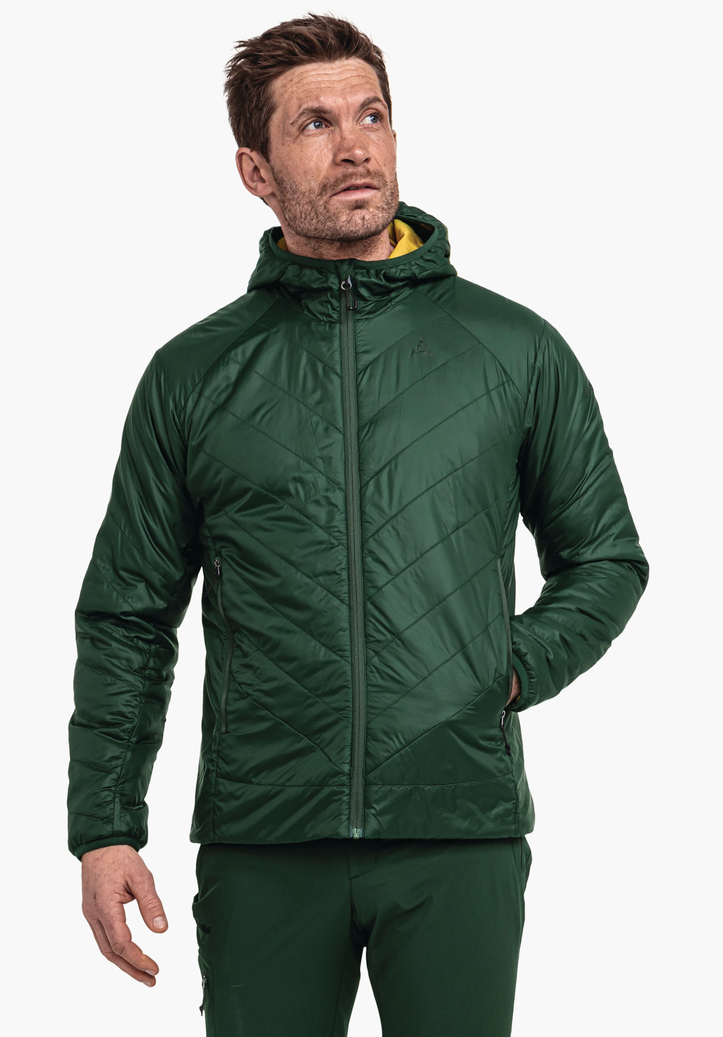 Ins Jacket Style Cascata MNS dark green hooded jacket with yellow inner lining, worn by a man looking up to the right; Schöffel logo on the chest; light neutral background.