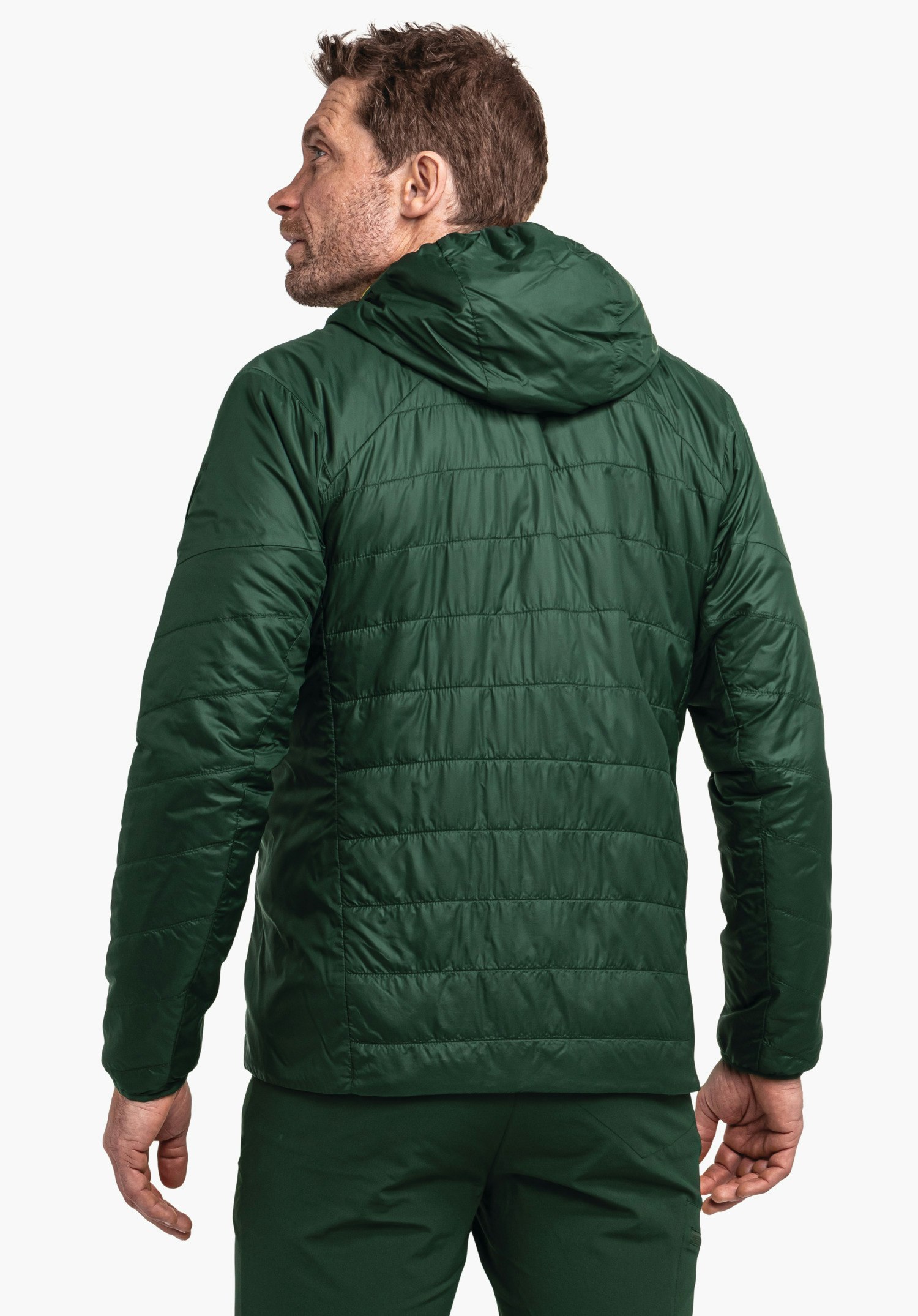 Ins Jacket Style Cascata MNS Dunkelgrüne gesteppte Jacke, getragen von einem Mann, der nach links blickt; Kapuze am Rücken, stehende Pose vor hellem einfarbigem Hintergrund.