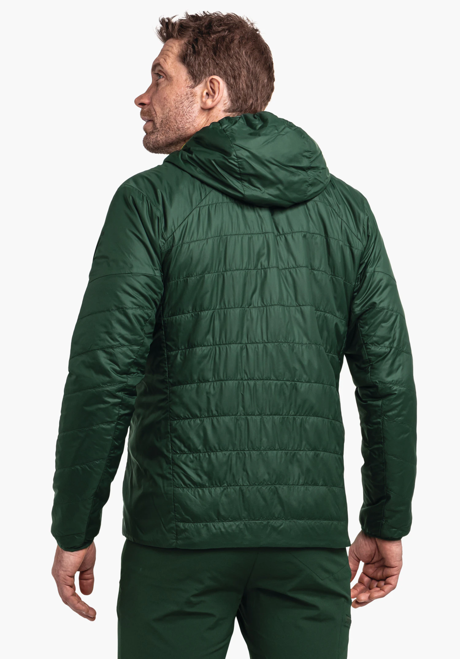 Ins Jacket Style Cascata MNS dark green quilted jacket worn by a man looking to the left; hood resting on the back; standing pose against a light plain background.