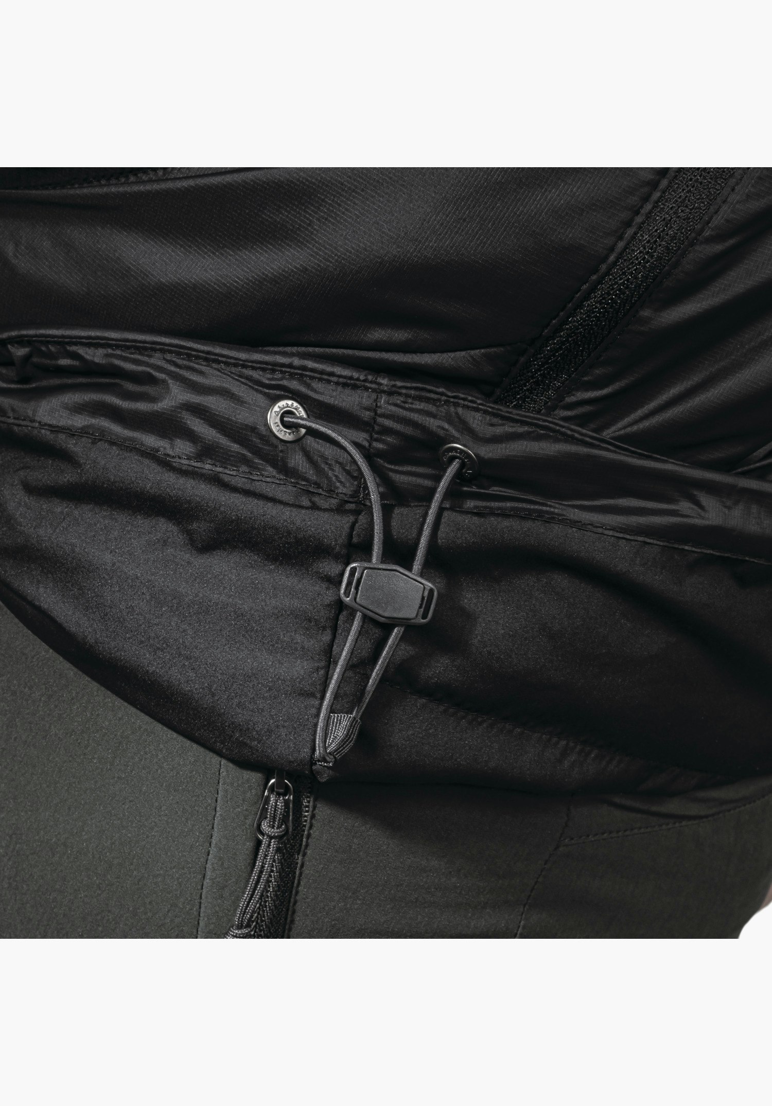 Ins Jacket Style Cascata MNS. Detail of the adjustable drawcord with toggle and black metal eyelets alongside adjacent zips. Close-up against a white background.
