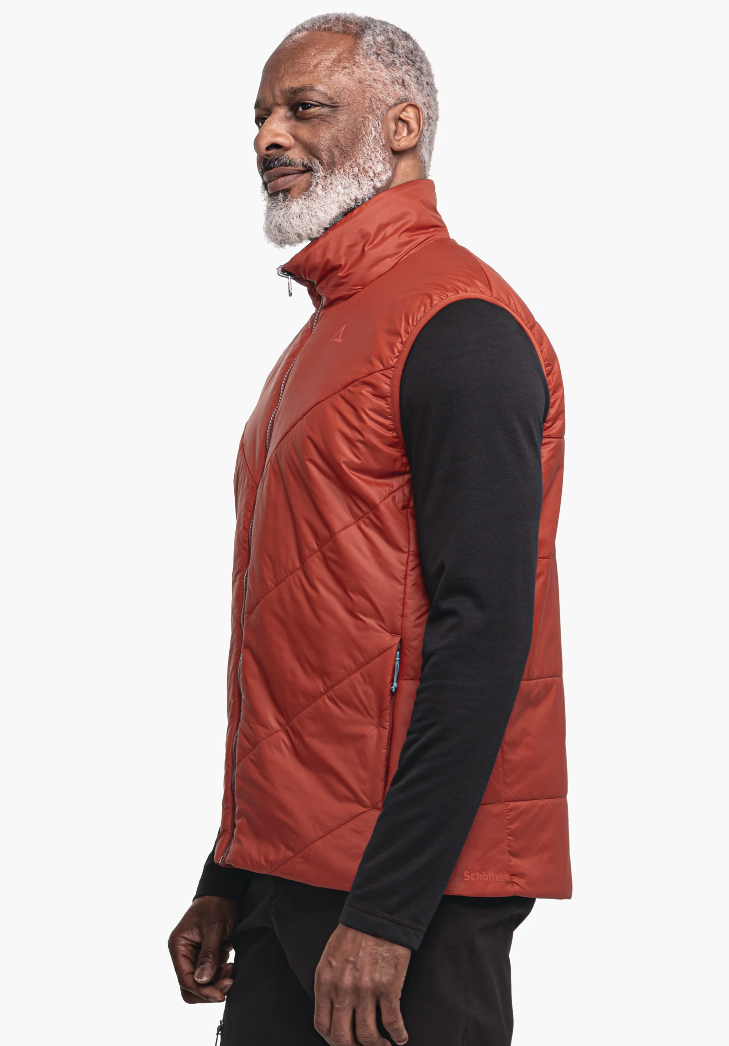Ins Vest Style Yew MNS donkerrode gewatteerde bodywarmer met Schöffel-logo op de borst, zijwaarts gedragen; model staat rustig, draagt een zwart shirt met lange mouwen en een zwarte broek voor een lichte achtergrond. Tekst: Schöffel.
