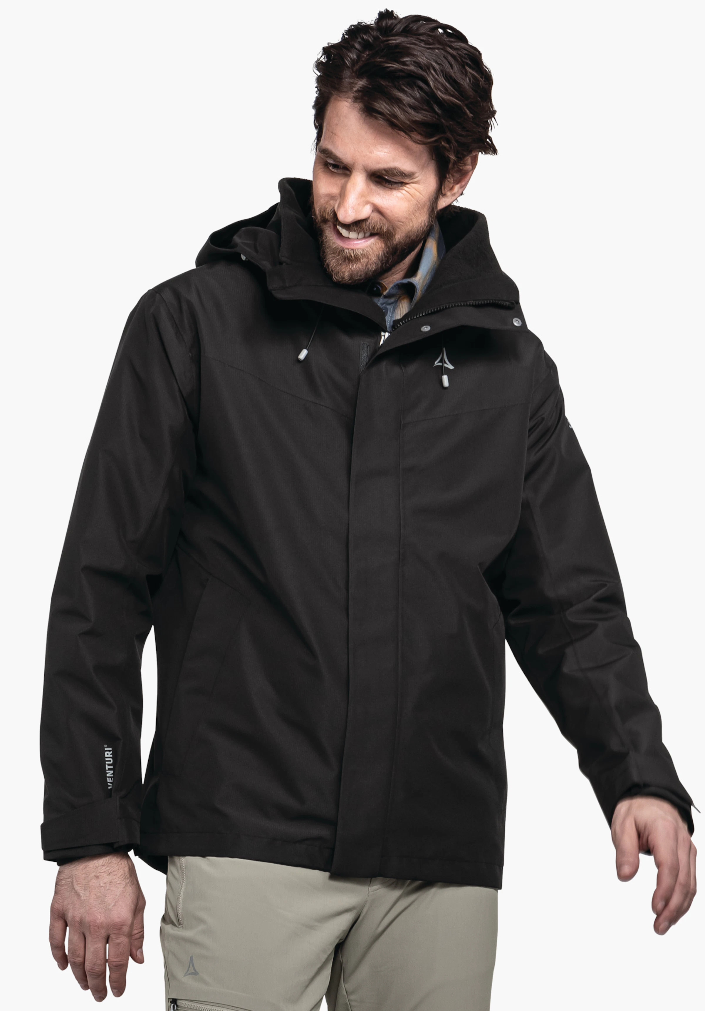 3in1 Jacket Style Okere MNS schwarze Jacke — Mann trägt sie, lächelt und blickt leicht nach unten; Kapuze an; Schöffel-Logo auf der Brust; Ärmeltext: VENTURI; weißer Hintergrund.
