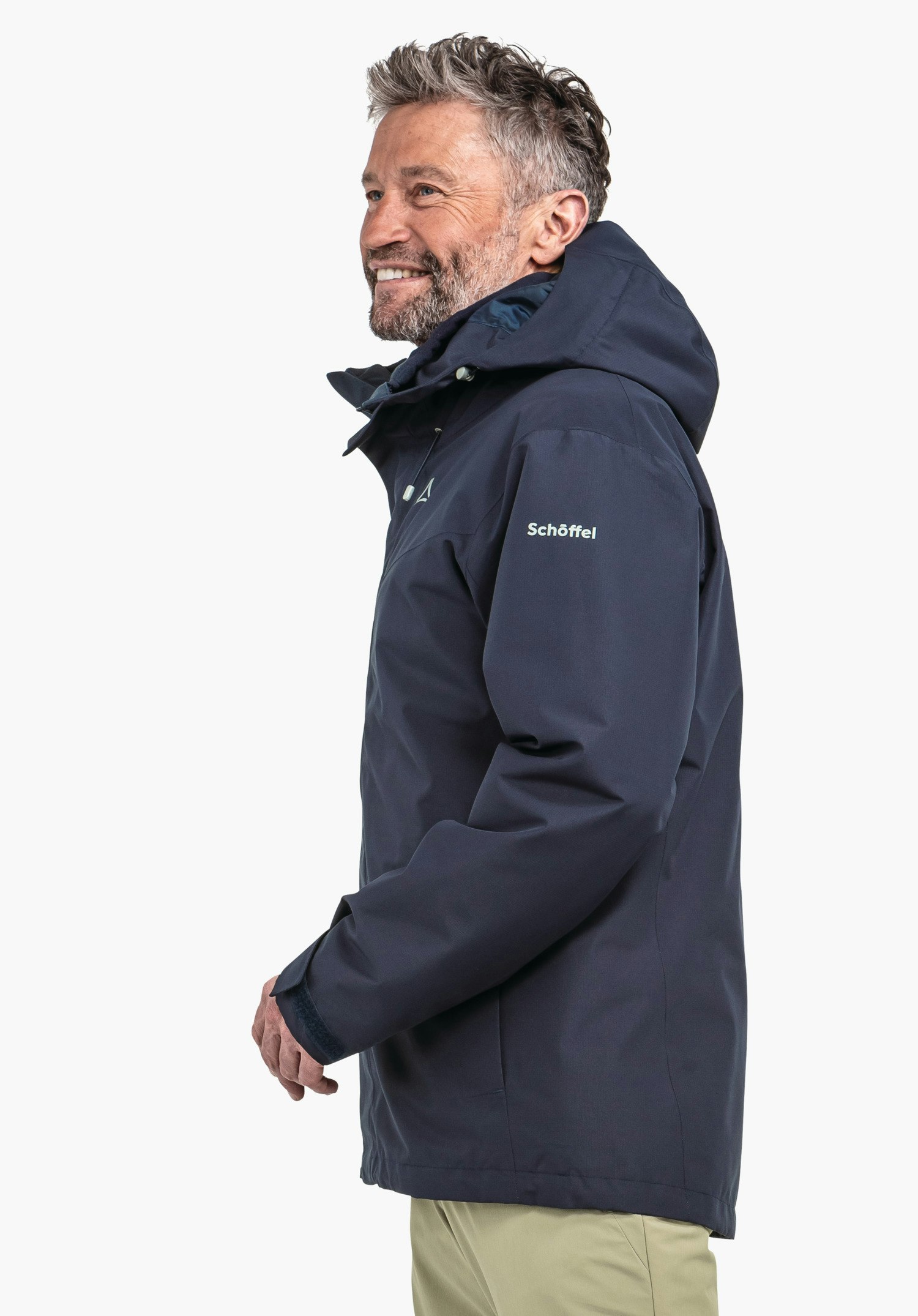 3in1 Jacket Style Okere MNS dunkel blau Jacke, Mann lächelt im Profil, trägt Kapuze, steht seitlich vor weißem Hintergrund; Schöffel-Logo sichtbar auf Brust, Schriftzug "Schöffel" auf Ärmel.