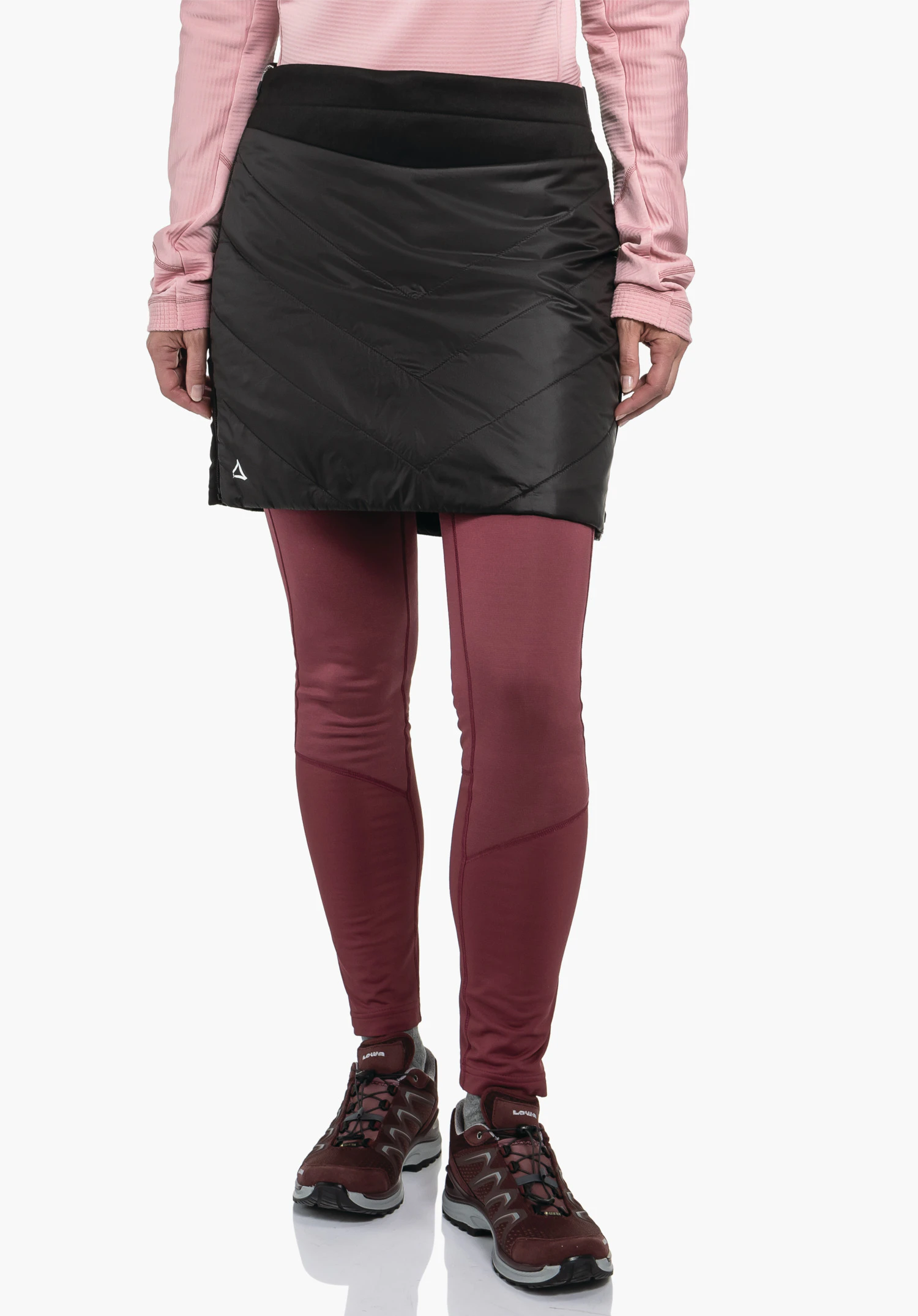 Ins Skirt Style Cascata WMS Jupe matelassée noire portée sur un legging rouge foncé; personne debout sur fond blanc, haut rose clair visible; logo Schöffel à l’ourlet, marquage: LOWA.