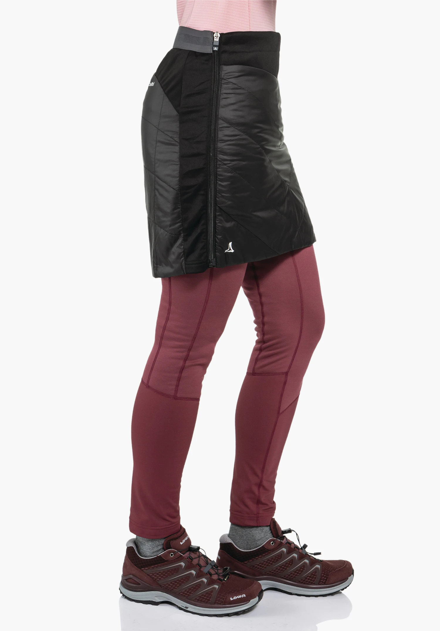 Ins Skirt Style Cascata WMS zwarte gewatteerde isolatierok gedragen over donkerrode leggings; persoon staat zijwaarts voor een witte studioachtergrond. Wit Schöffel-logo aan de zoom. Zichtbare tekst: "LOWA" op de schoen.