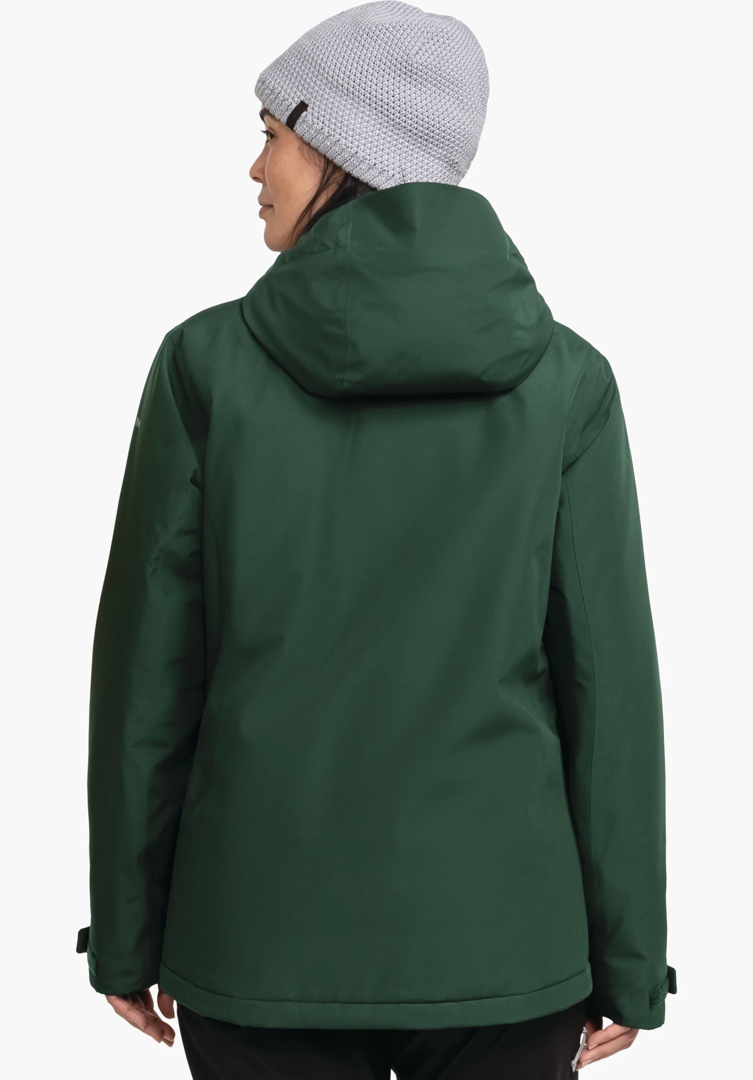 Ins Jacket Style Wildkar WMS veste vert foncé, vue de dos, portée par une personne avec un bonnet en maille gris clair; capuche en place. Fond blanc neutre, posture debout.