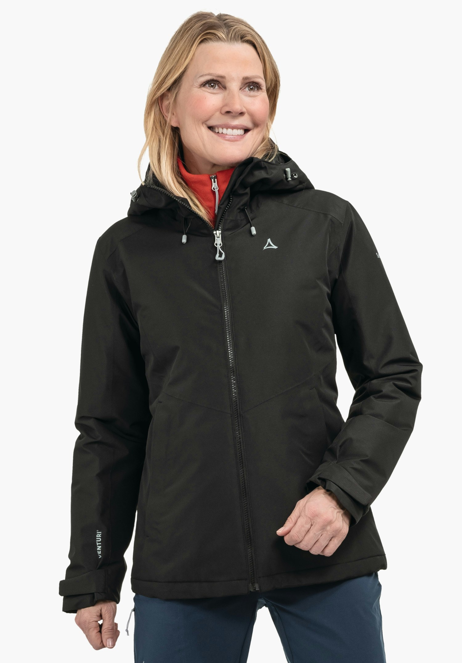 Ins Jacket Style Wildkar WMS Veste noire avec logo Schöffel; femme la porte zippée, souriante; col rouge visible, pantalon bleu, fond clair neutre. Texte sur la manche: «VENTURI».