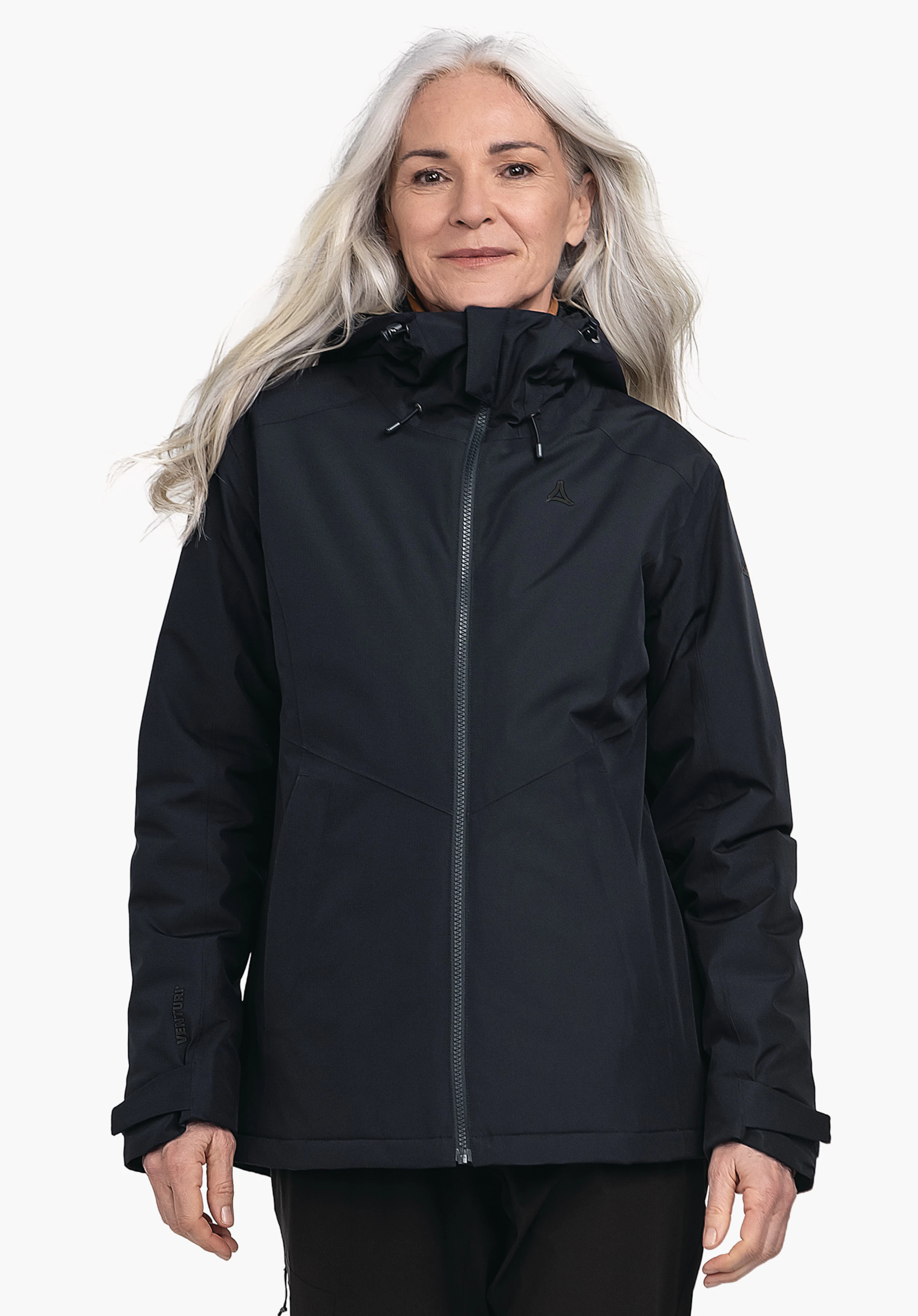 Ins Jacket Style Wildkar WMS dunkelblaue Jacke, von älterer Frau getragen; Reißverschluss geschlossen; Schöffel-Logo auf der Brust; Ärmelbeschriftung "VENTURI"; Kapuze hochgezogen; neutraler heller Hintergrund.