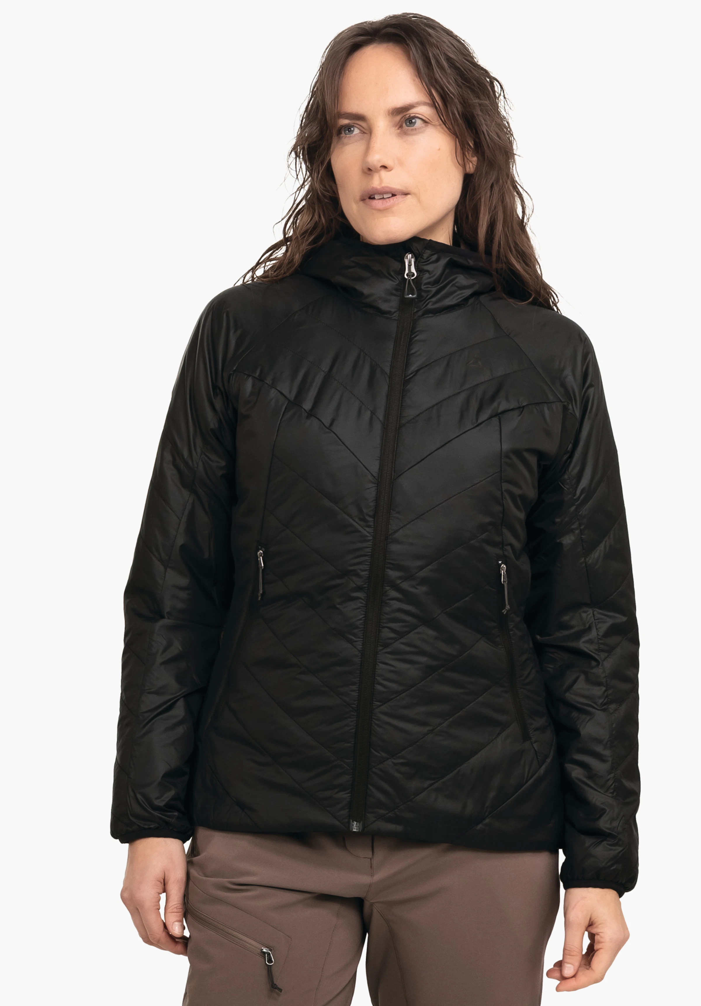Ins Jacket Style Cascata WMS Damenjacke, schwarz, wird von einer Frau getragen; Reißverschluss geschlossen, Kapuze aufgesetzt, seitliche Taschen sichtbar; Schöffel-Logo auf der Brust; Frau blickt nach rechts, vor hellem Hintergrund.