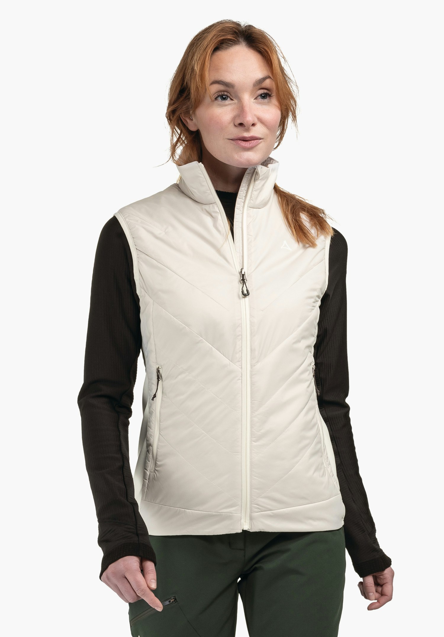 Hybrid Vt Style Cascata WMS Gilet matelassé blanc lumineux porté par une femme; logo Schöffel visible sur la poitrine gauche; combiné avec un haut noir à manches longues et un pantalon vert foncé devant un fond studio clair.