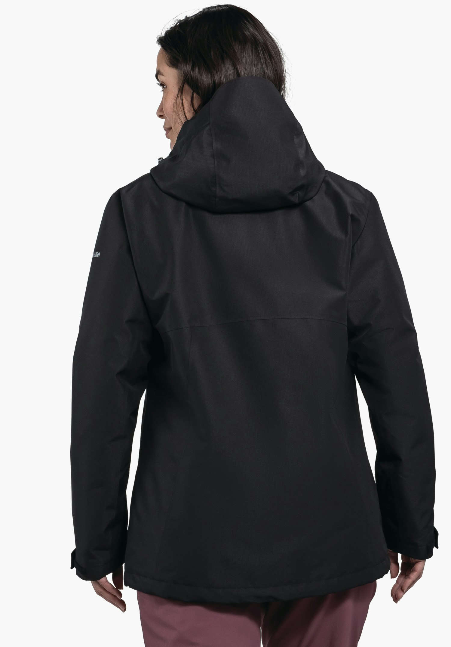 3in1 Jacket Style Okere WMS veste noire, portée de dos par une femme, capuche relevée, posture debout, regard tourné vers la gauche; fond blanc.