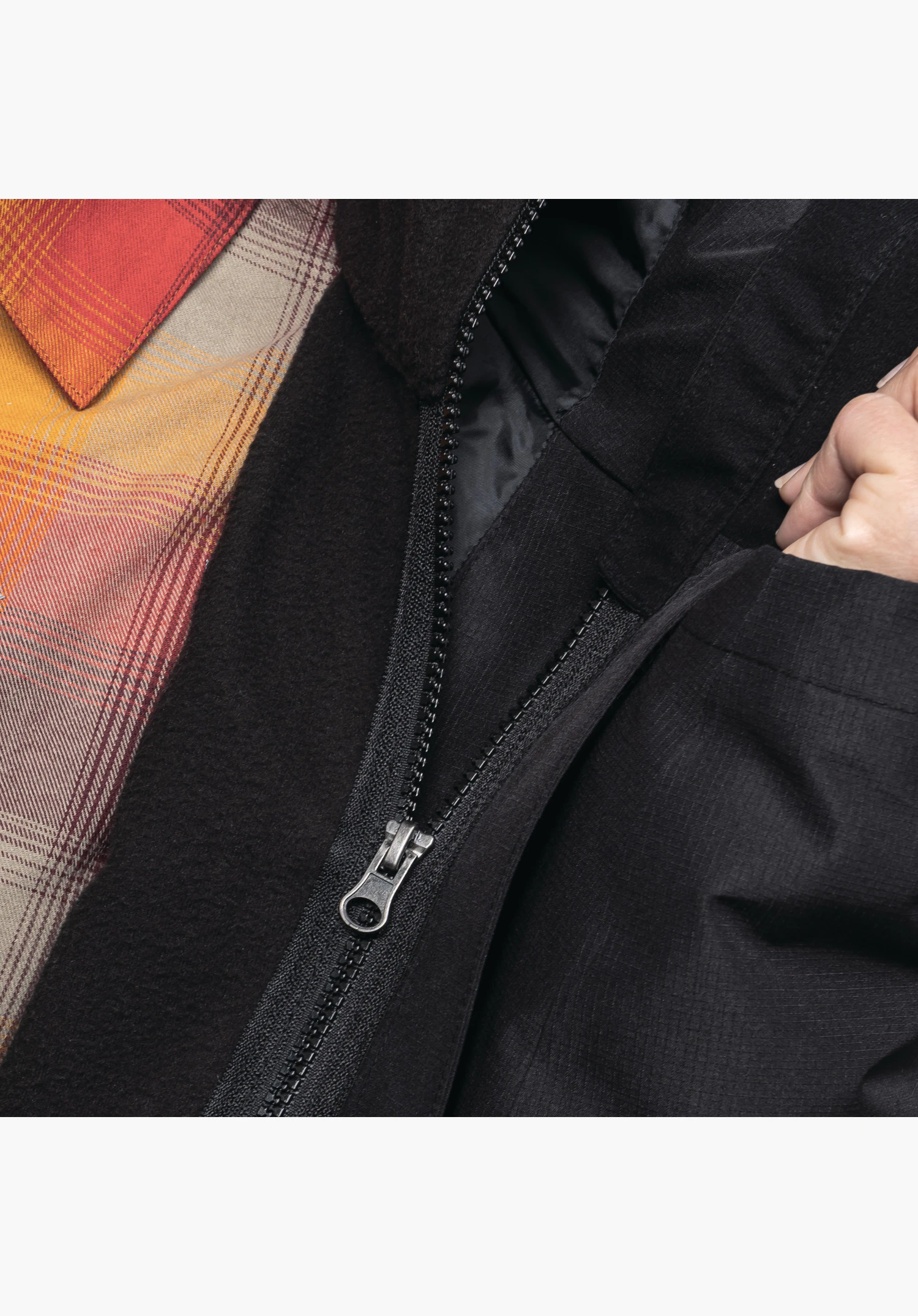 3in1 Jacket Style Okere WMS zeigt den Reißverschluss, der die schwarze Innenjacke mit der Außenjacke verbindet, in einer Nahaufnahme vor weißem/neutralem Hintergrund.