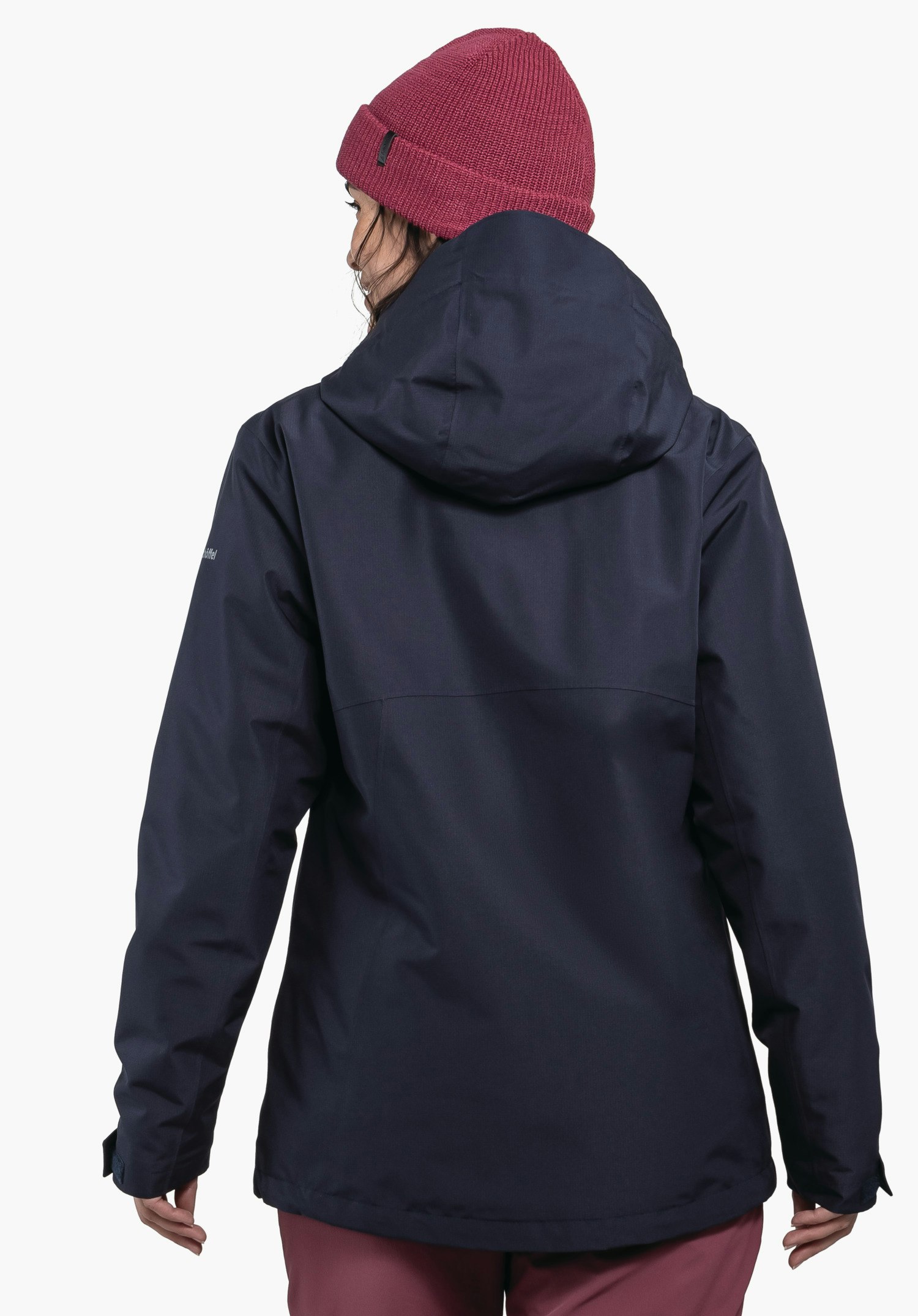 3in1 Jacket Style Okere WMS veste à capuche bleu foncé, portée par une personne tournant légèrement la tête sur le côté; bonnet en maille rouge foncé et pantalon rouge foncé; fond blanc.