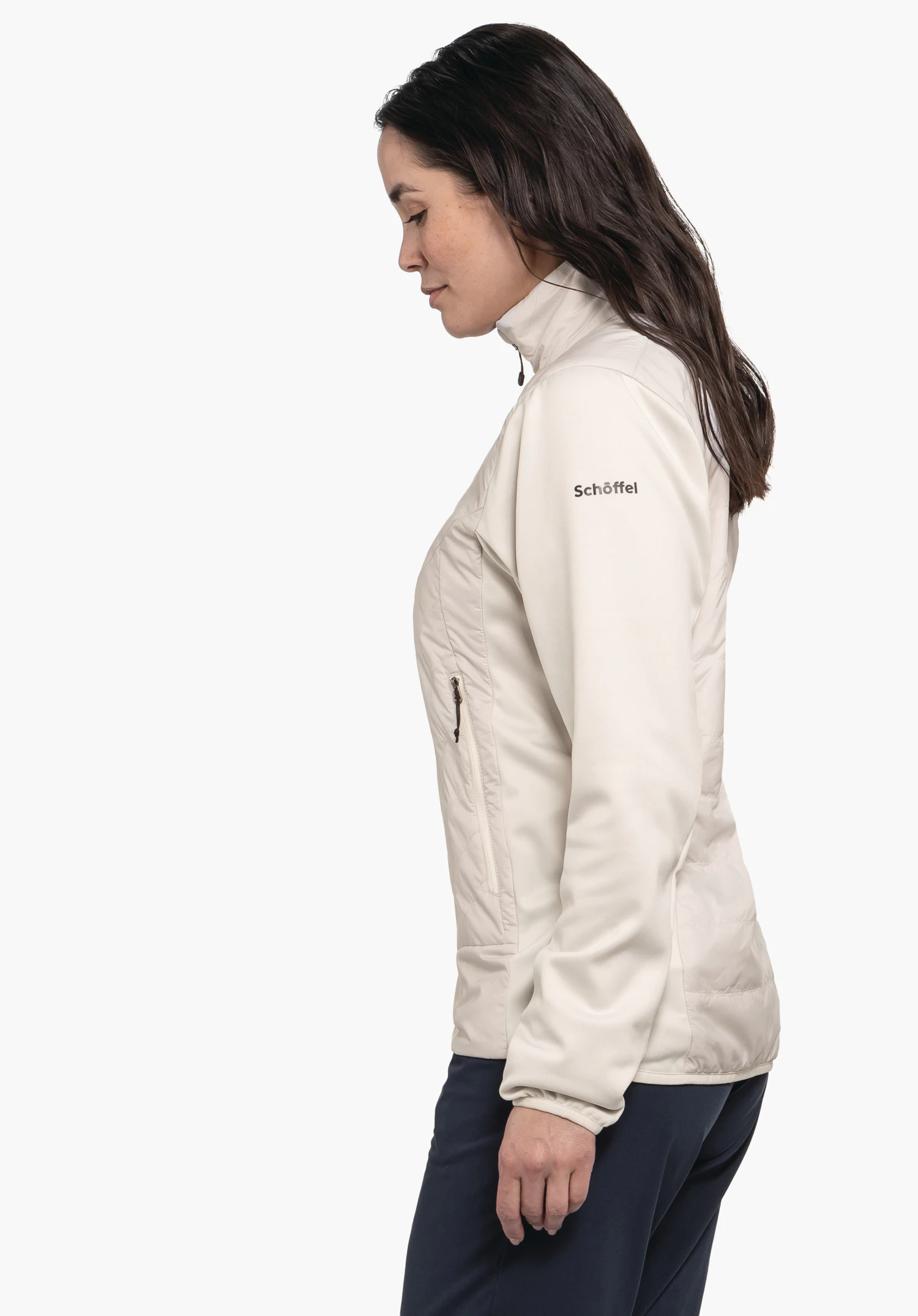 Hybrid Jk Style Cascata WMS light white jacket worn side-on by a woman with dark brown hair; she stands calmly in front of a white background. Text on sleeve: "Schöffel". Dark blue trousers.