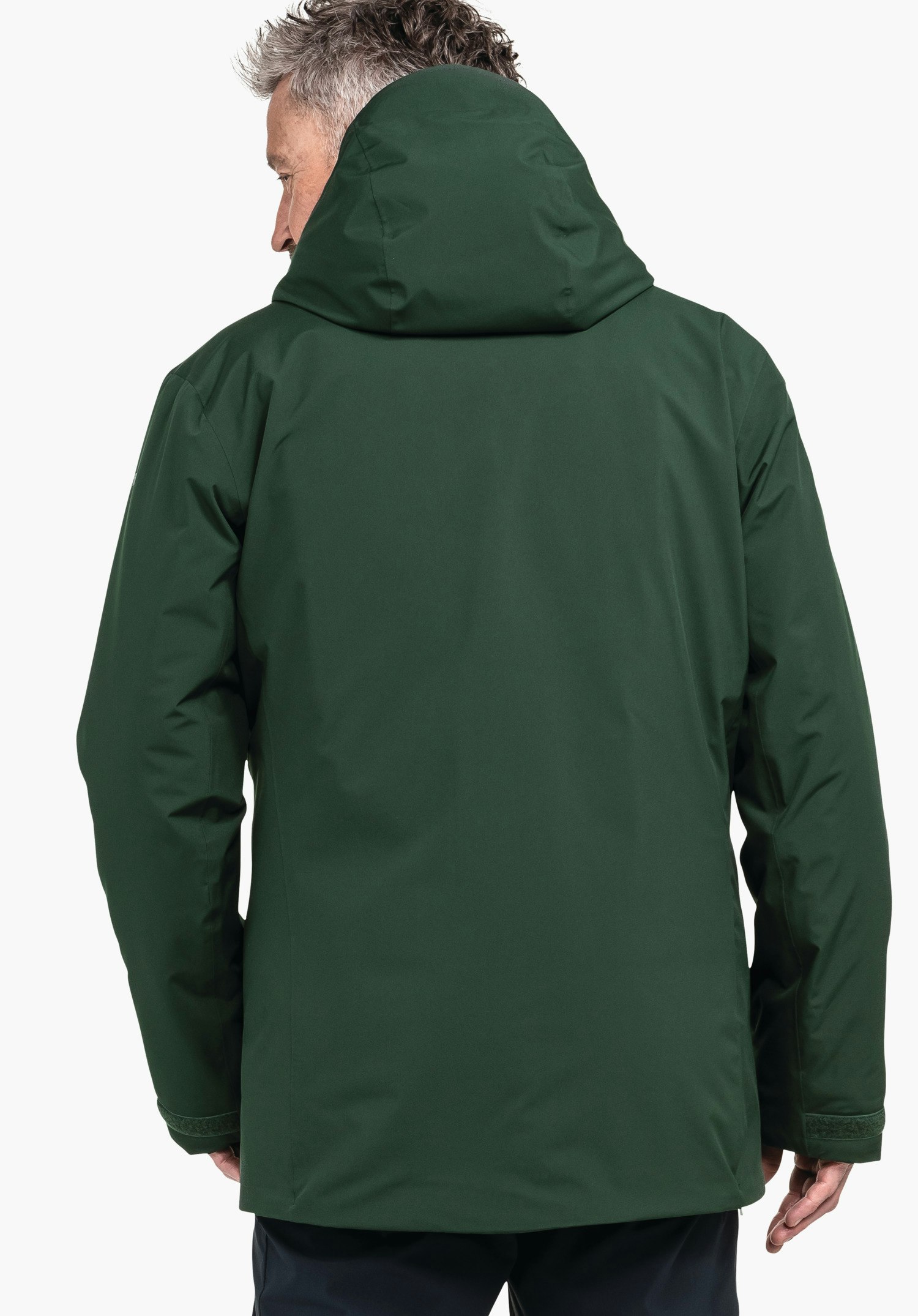 Parka Style Froda MNS dunkelgrüne Jacke, von hinten getragen; Person steht, leicht nach links gewandt, Kapuze hochgezogen; sichtbarer Rücken und Ärmel vor neutralem hellen Hintergrund.