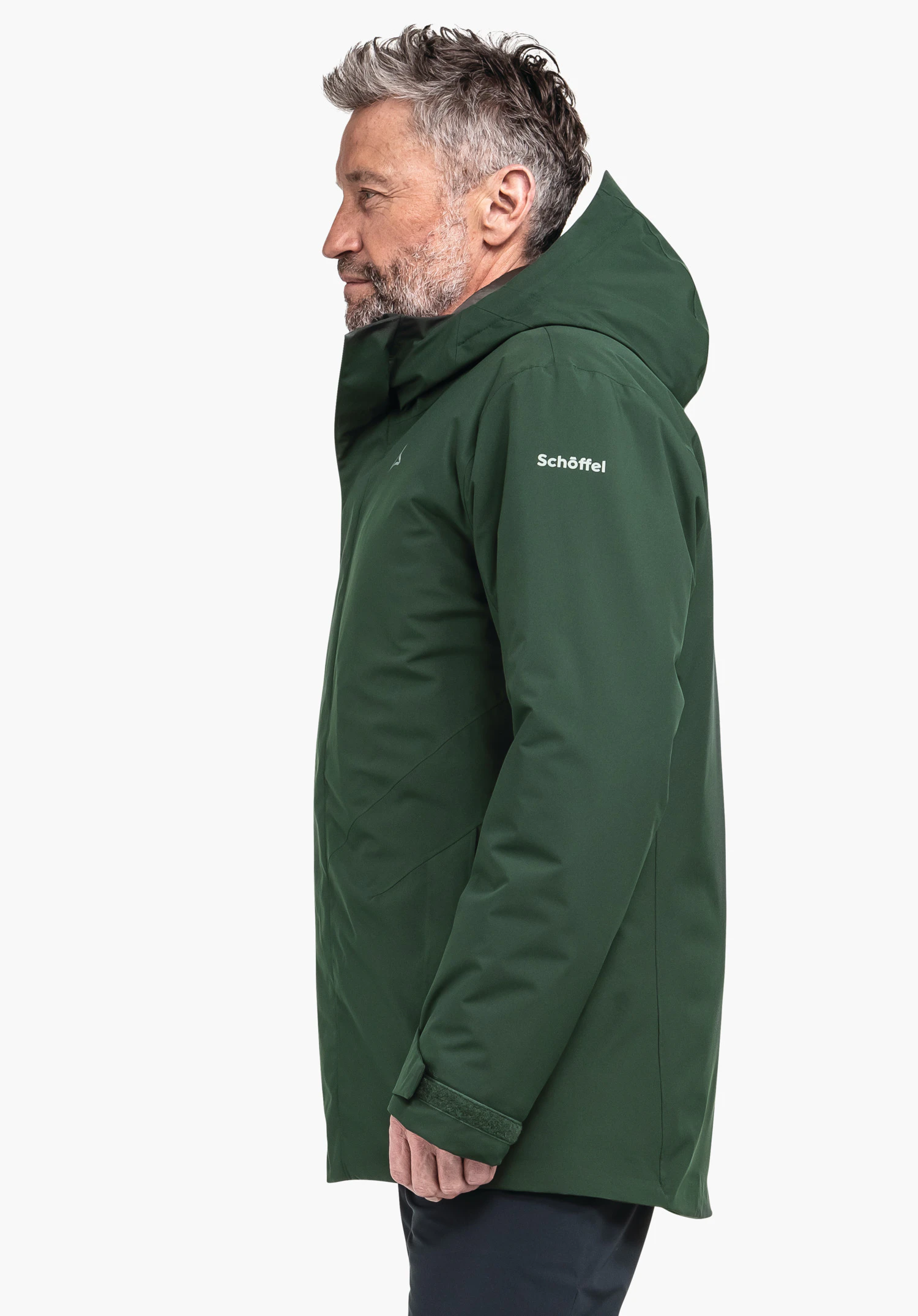 Parka Style Froda MNS dark green jacket worn by a man in profile, hood raised, in front of a white background. On the upper arm the text "Schöffel" is visible. Schöffel logo on the chest.