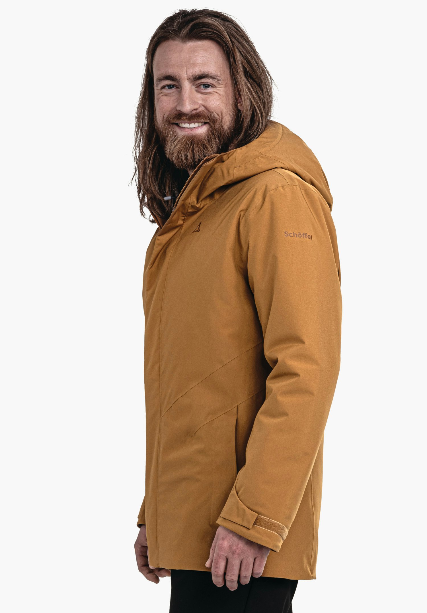 Parka Style Froda MNS man with a dark orange jacket and long hair smiles and stands side-on; Schöffel logo on the chest, lettering "Schöffel" on the sleeve; light neutral background.