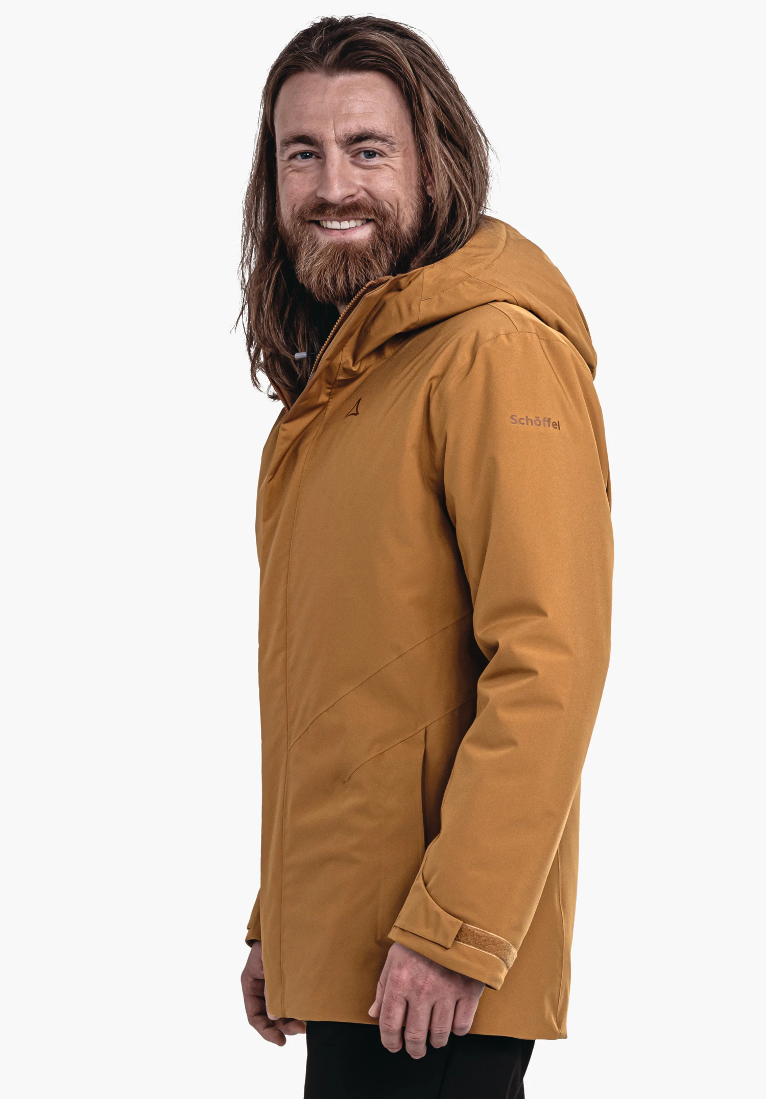 Parka Style Froda MNS man with a dark orange jacket and long hair smiles and stands side-on; Schöffel logo on the chest, lettering "Schöffel" on the sleeve; light neutral background.