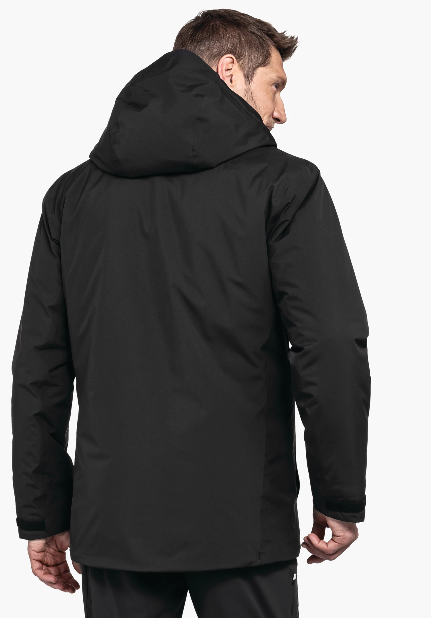Parka Style Froda MNS Jacke, schwarz, mit Kapuze; ein Mann trägt sie von hinten, steht vor hellem neutralen Hintergrund.