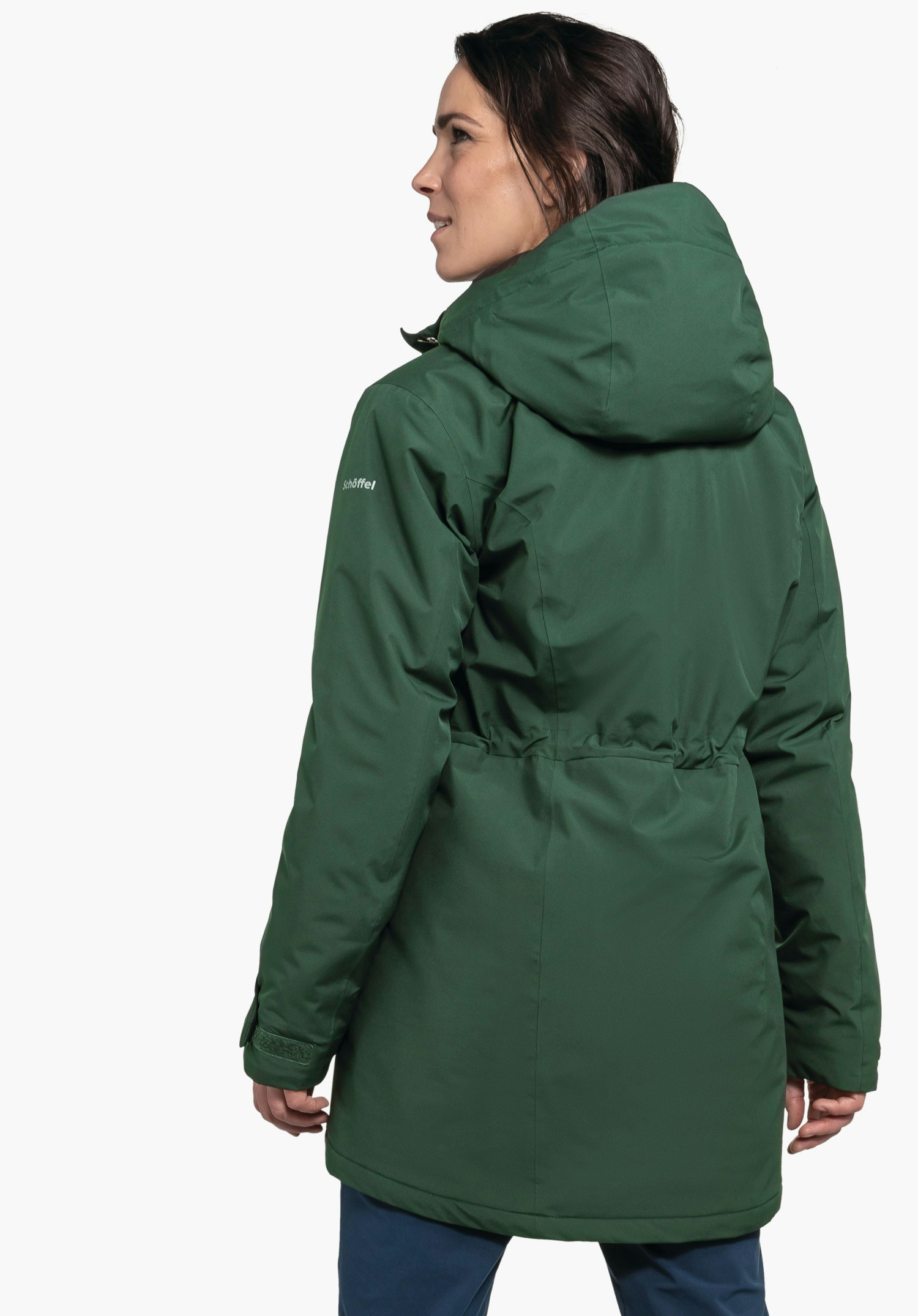 Parka Style Froda WMS parka vert foncé; porté par une femme de dos regardant sur le côté, devant un fond studio blanc. Texte sur la manche: « schöffel ».