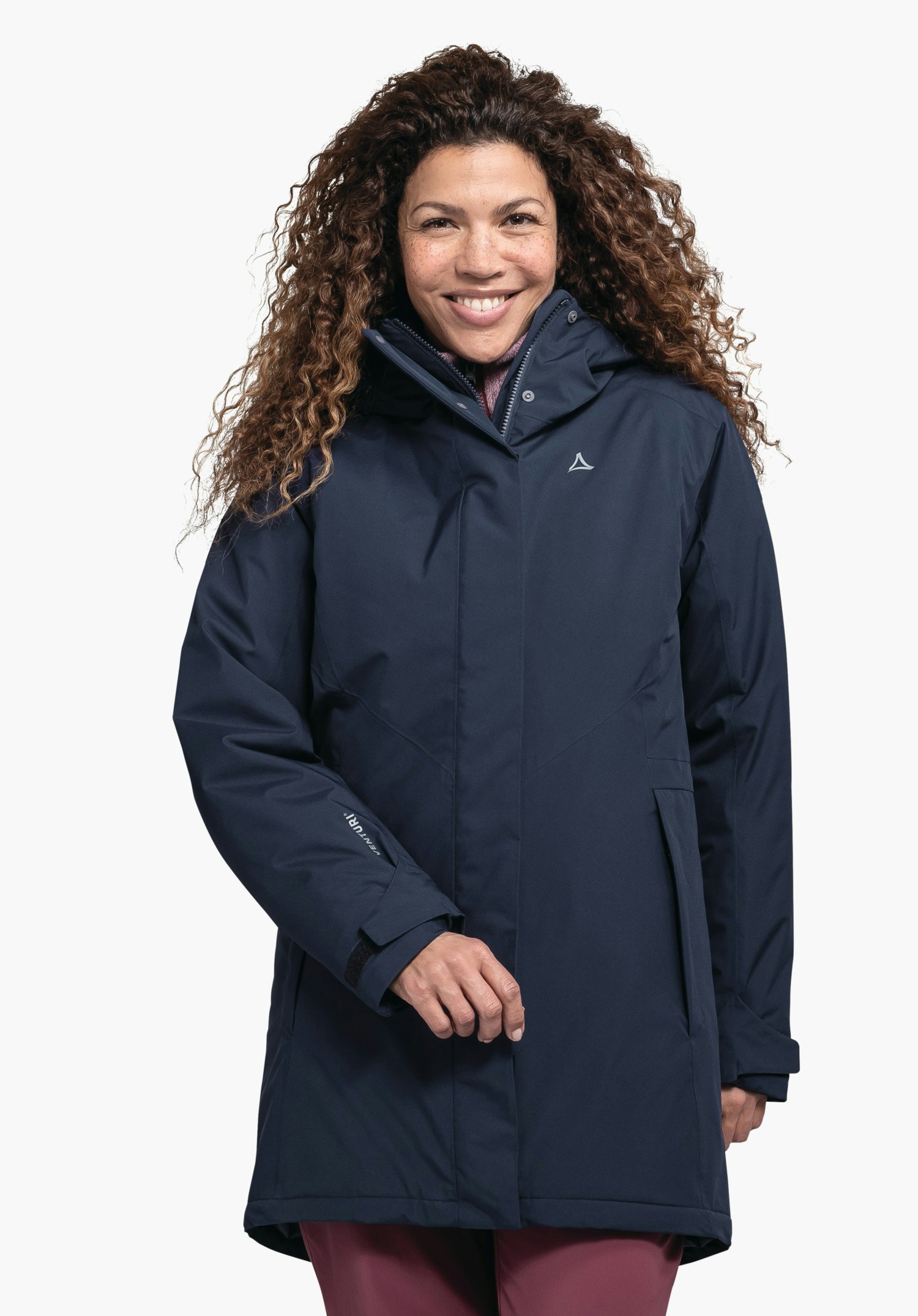 Parka Style Froda WMS Parka bleu foncé à capuche avec logo Schöffel, portée par une personne souriante debout de face devant un fond blanc.