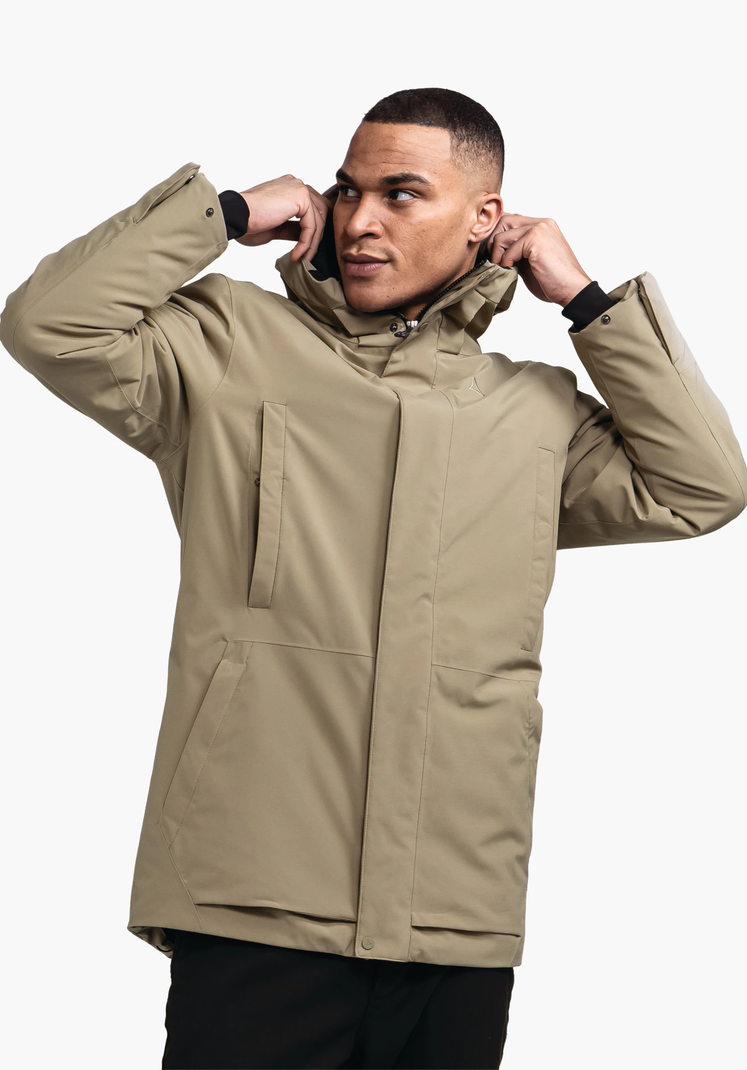 Ins Parka Style Crivat MNS hellgrüne Jacke mit Schöffel-Logo; Mann zieht Kapuze hoch, richtet sie am Hals; halbseitige Brustaufnahme vor einfarbigem hellem Hintergrund.