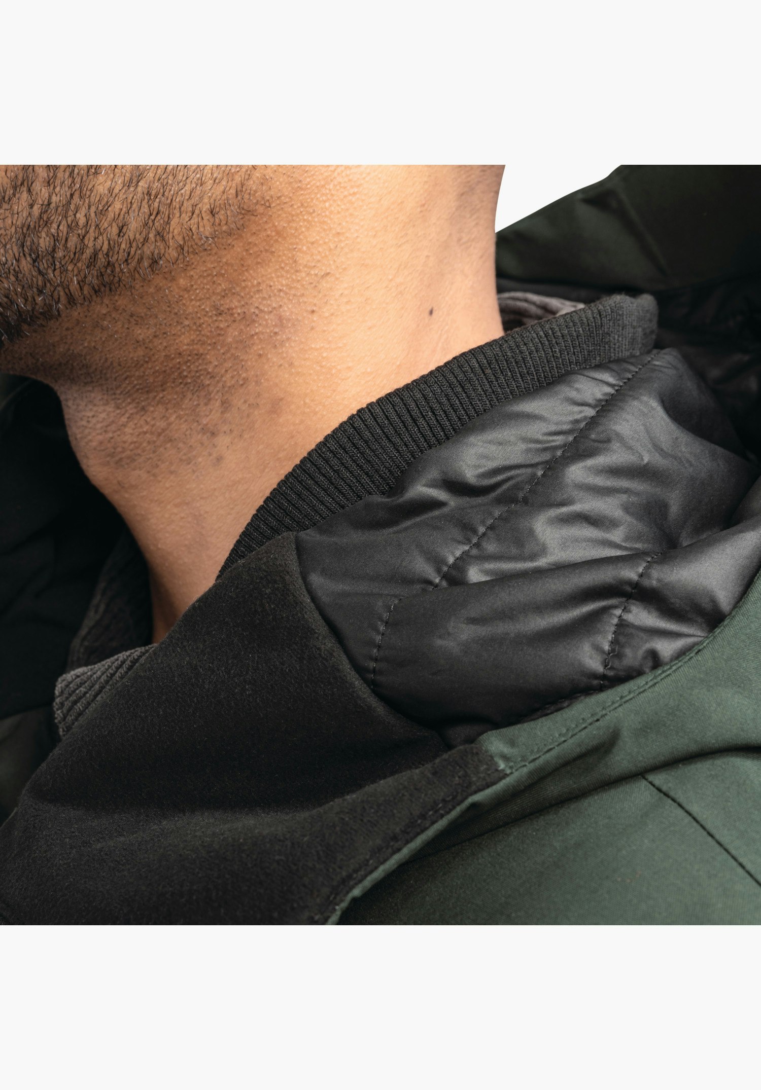 Ins Parka Style Crivat MNS zeigt den Kragenbereich mit grünem Oberstoff, weichem Innenbesatz und einem wärmenden Rippstrick-Kragen am Hals. Nahaufnahme vor weißem Hintergrund.