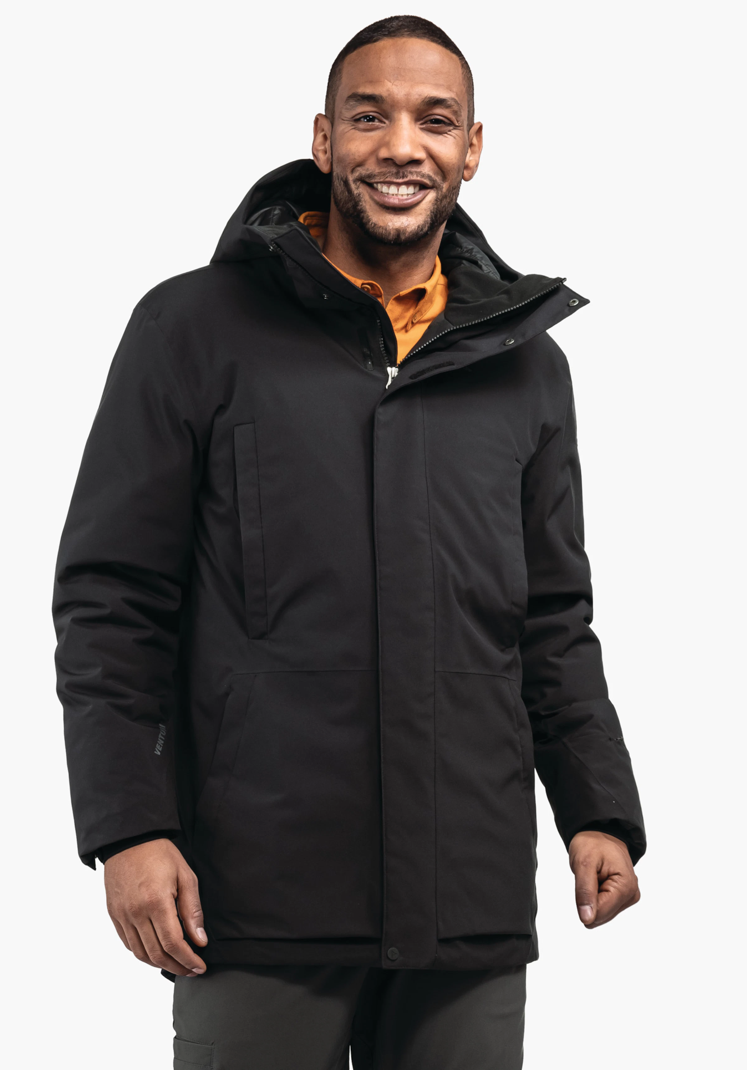 Ins Parka Style Crivat MNS veste d’hiver noire, portée par un homme souriant; debout de face, mains le long du corps, capuche relevée; contexte: fond blanc. Texte sur la manche: «VENTURI».