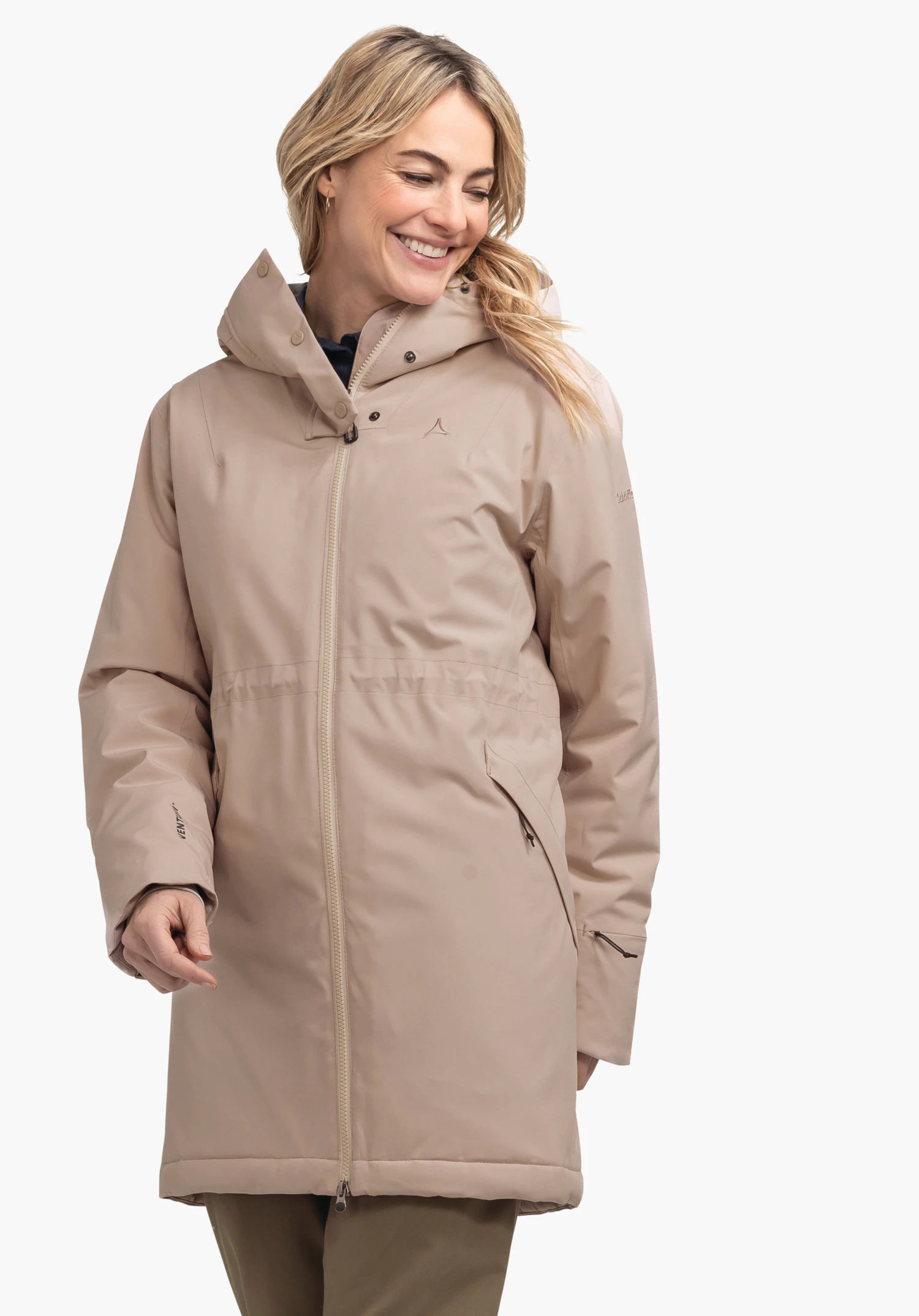 Ins Parka Style Crivat WMS light brown women’s parka with Schöffel logo on the chest; worn by a smiling person looking downwards; hood on; plain white background.