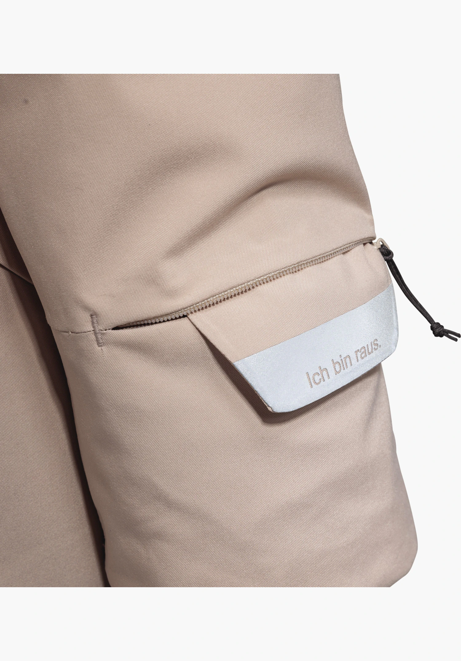 Ins Parka Style Crivat WMS shows a detail of the pocket with zip and reflective element featuring the lettering 'Ich bin raus.' on the pink fabric. Close-up shot against a white/neutral background.