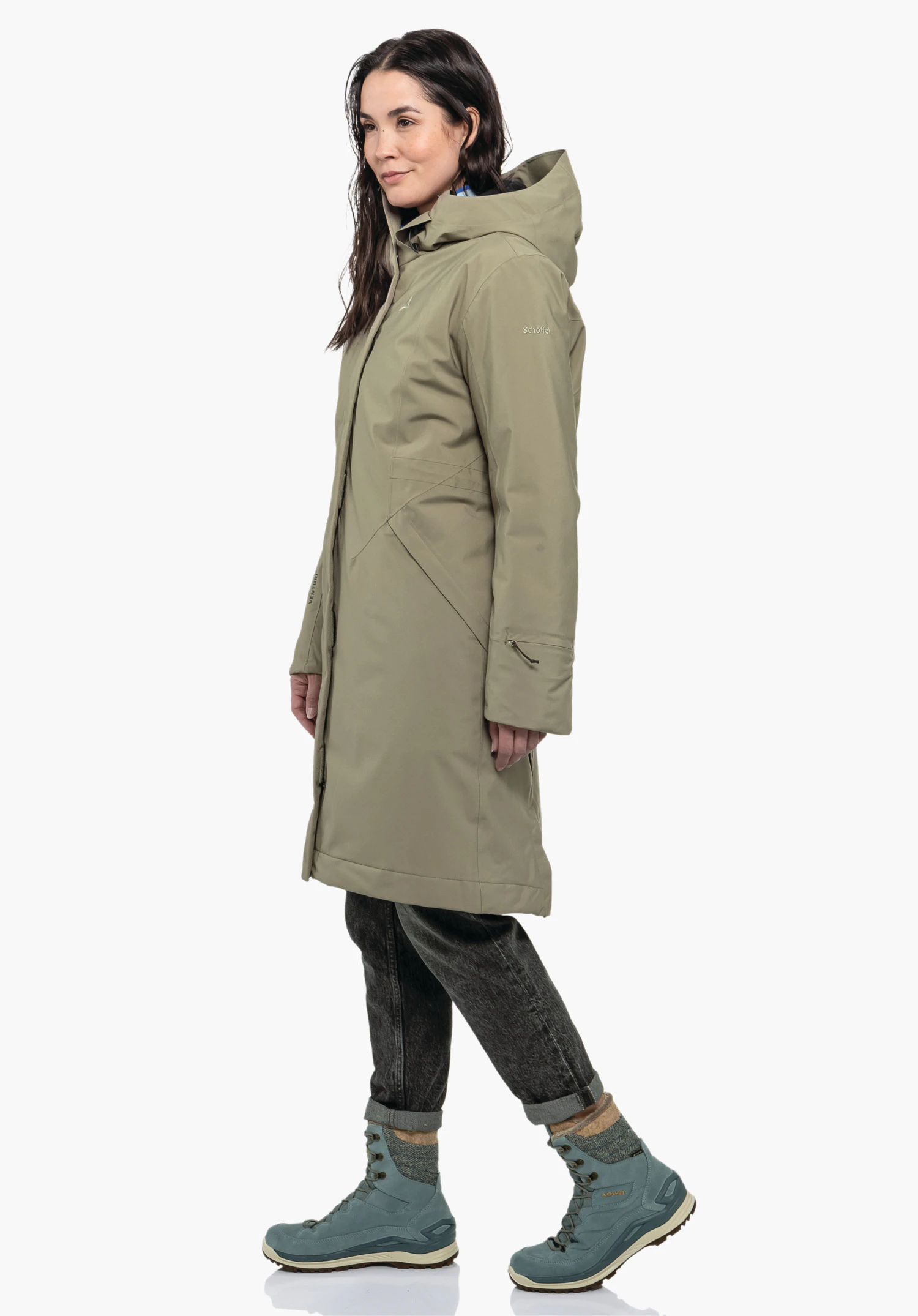Ins Coat Style Gregale WMS Hellgrüner Mantel mit Kapuze, von einer Frau seitlich stehend getragen; Kontext: weißer Studiohintergrund. Auf Ärmel: "Schöffel".