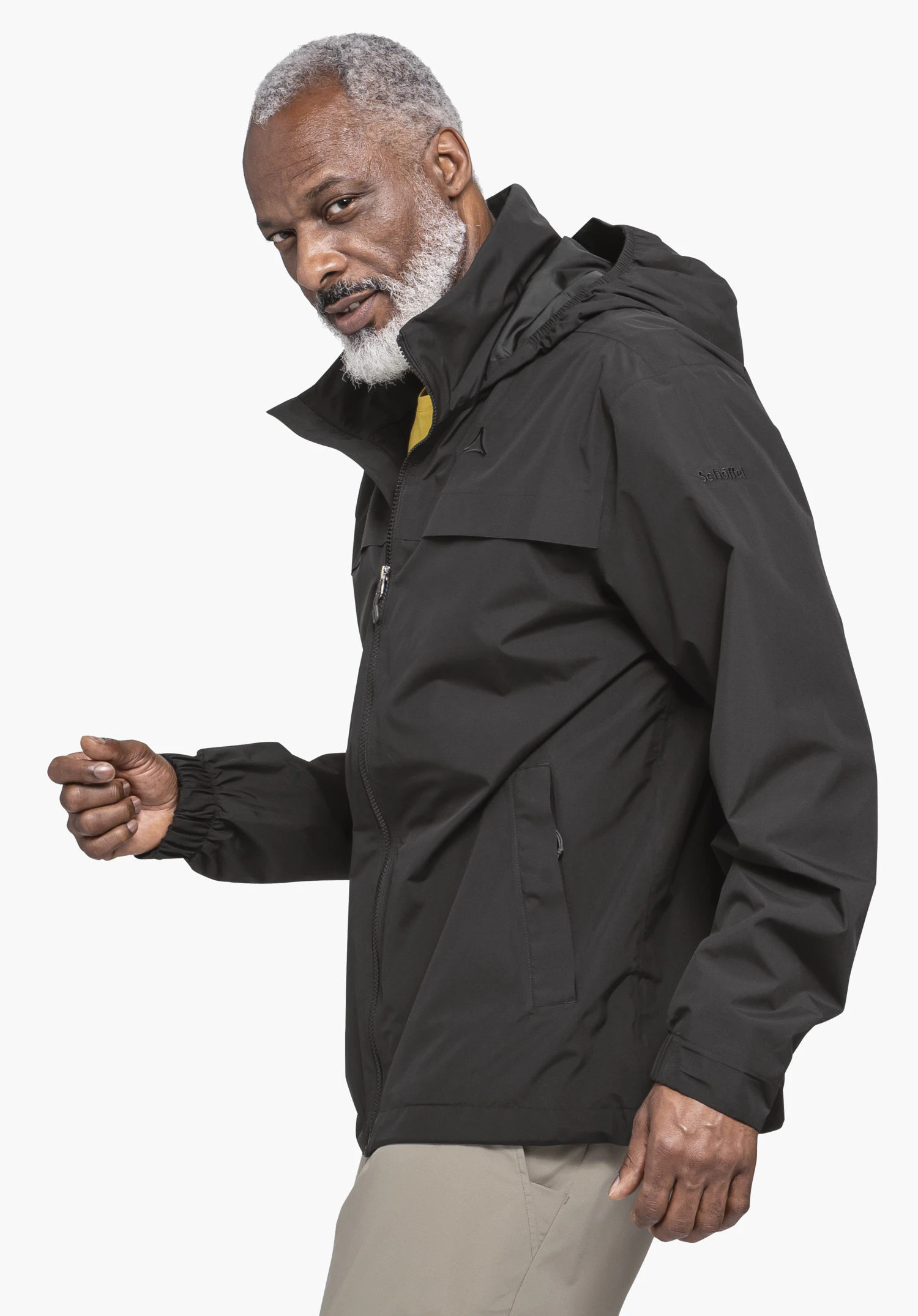 Jacket Style Bohorok MNS in Schwarz. Das Model steht seitlich und trägt die Jacke mit sichtbarem Schöffel-Logo auf der linken Brust und am Ärmel vor einem neutralen Hintergrund.