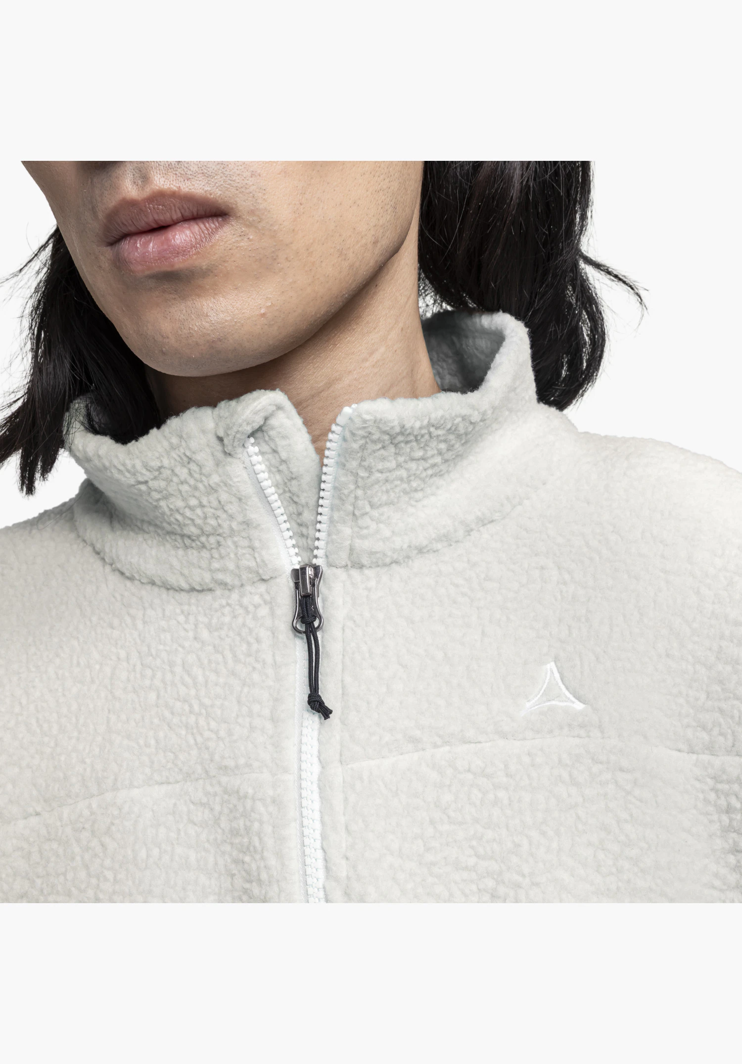 CIRC Fleece Jk Style Purga MNS focusing on the fluffy fleece fabric in natural, the half-open zip with a black cord puller and the embroidered Schöffel logo on the chest, close-up shot against a white background.