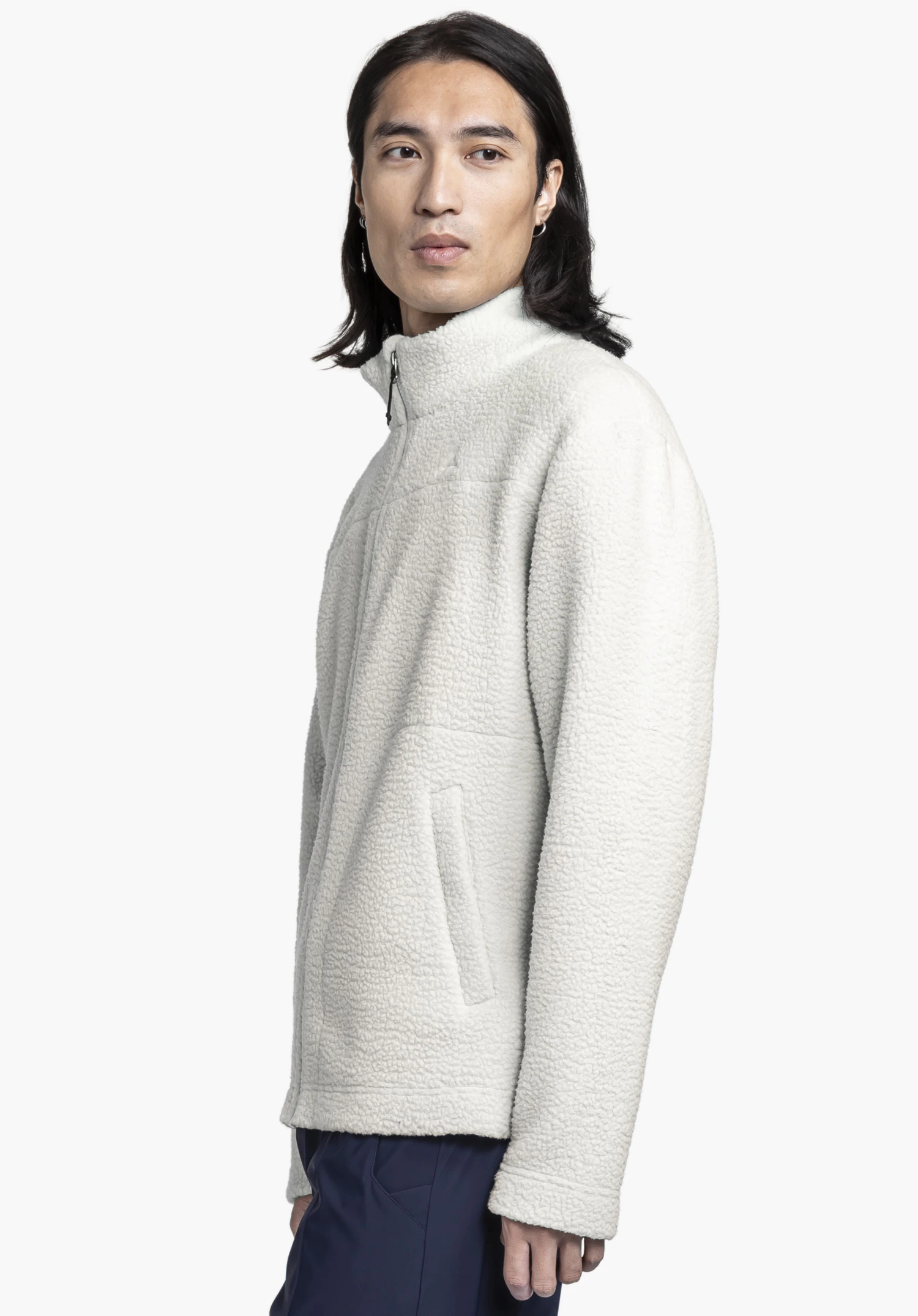 CIRC Fleece Jk Style Purga MNS: A model wears the jacket in the colour natur against a neutral background. Posed in a side-profile view, the textured fleece finish and the high stand-up collar are showcased to full effect.