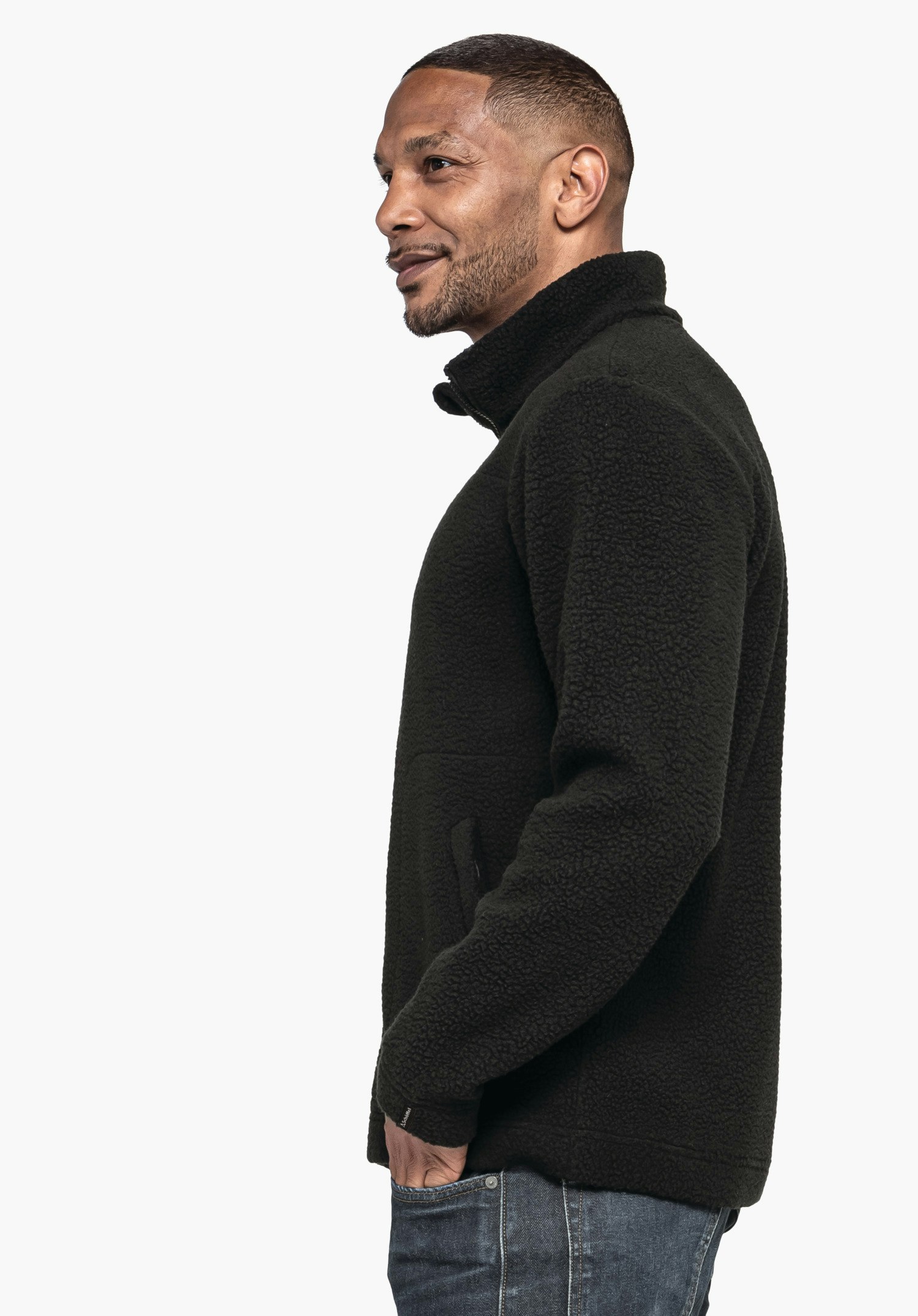 CIRC Fleece Jk Style Purga MNS: Ein Model steht seitlich vor einem neutralen Hintergrund und trägt das Fleece in Schwarz. Das dezente Schöffel-Logo am Ärmelabschluss unterstreicht den hochwertigen Look.