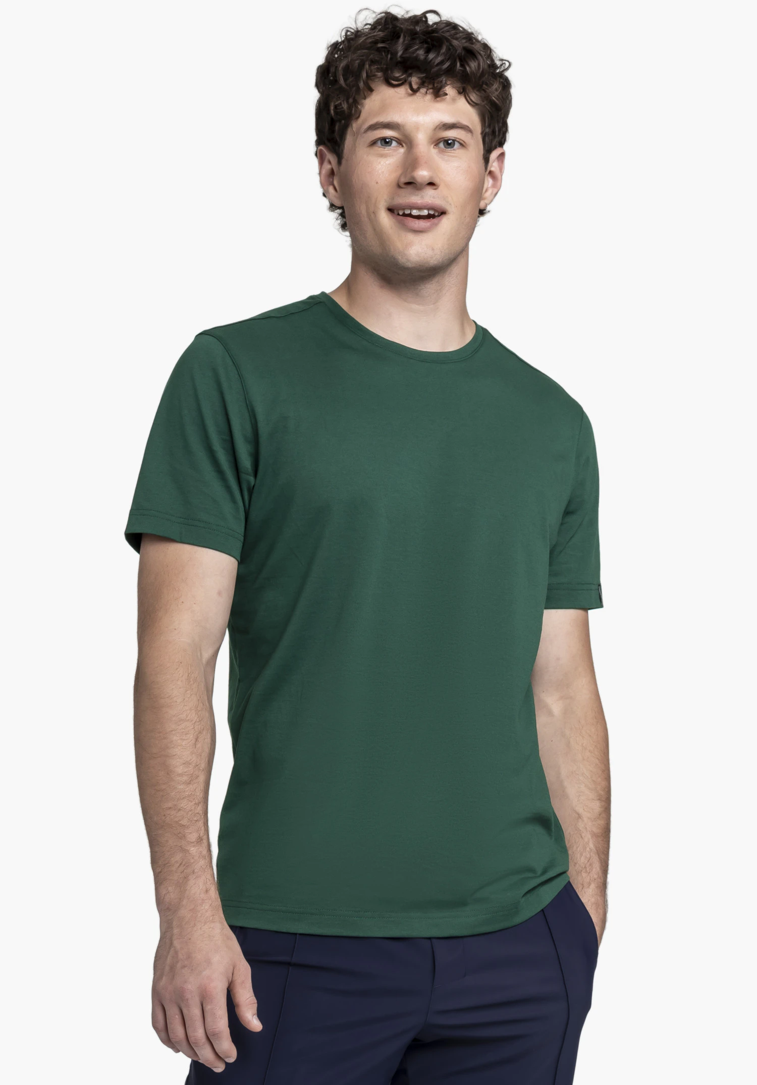 T Shirt Style Collada MNS in Grün: Ein Model präsentiert das Shirt vor einem neutralen Hintergrund und steht in einer aufrechten Pose. Das schlichte Design wird durch das kleine, dezente Schöffel-Logo am Ärmelsaum abgerundet.