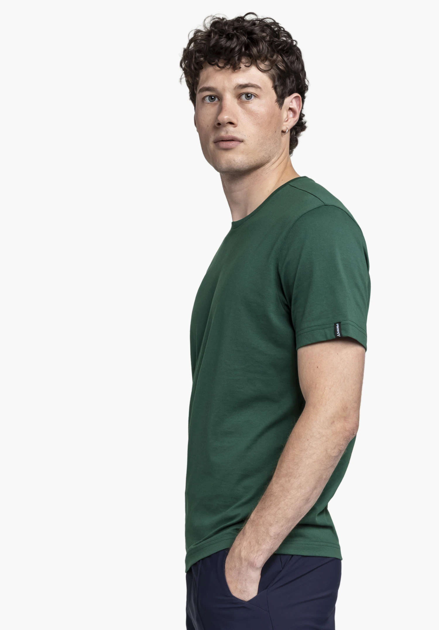 T Shirt Style Collada MNS en vert : Le mannequin est debout de profil devant un arrière-plan neutre et présente le t-shirt. Le logo Schöffel est visible sur la manche.